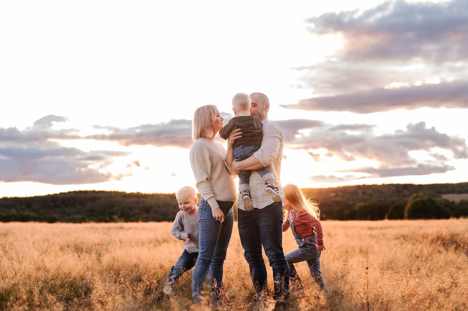 Family sharing joyful moment together in sunlit field at dusk.