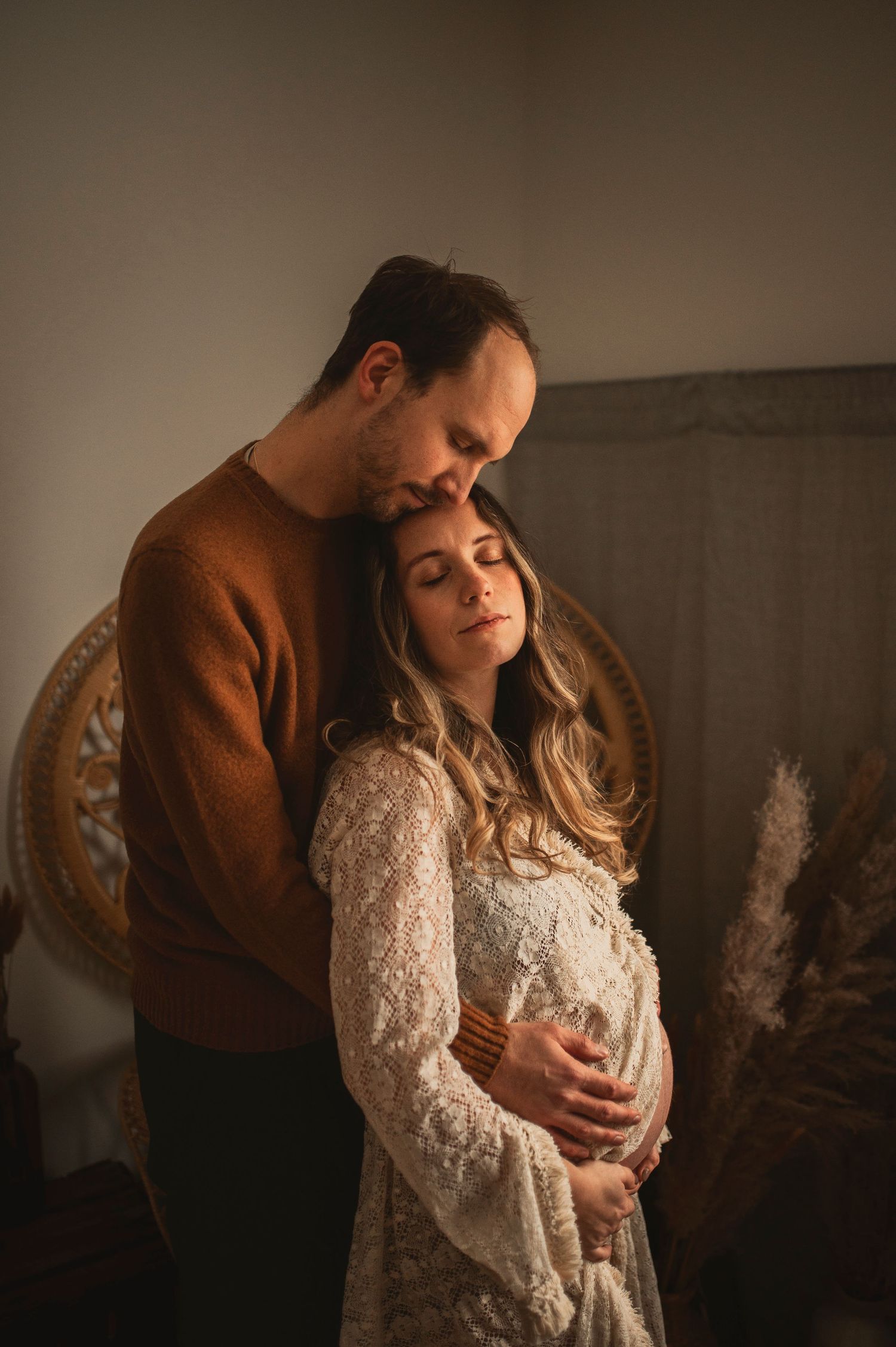 Intimate indoor portrait featuring a couple embracing, with warm lighting and vintage decor elements.