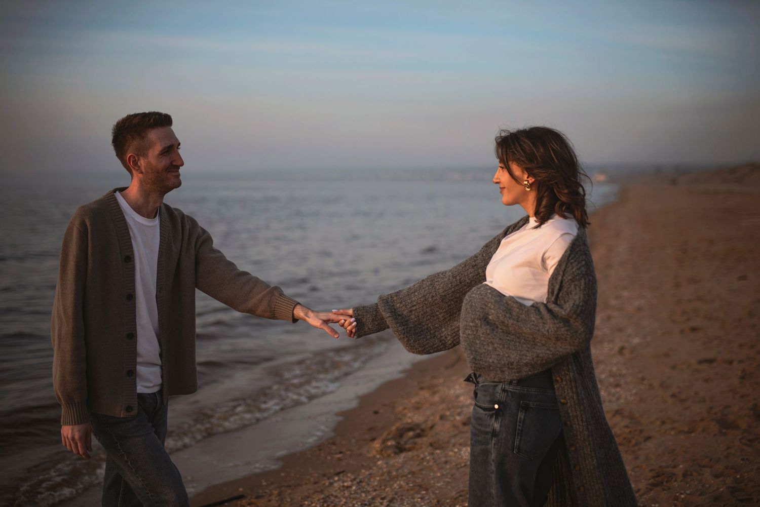 Couple sharing a playful moment on the beach at sunset.
