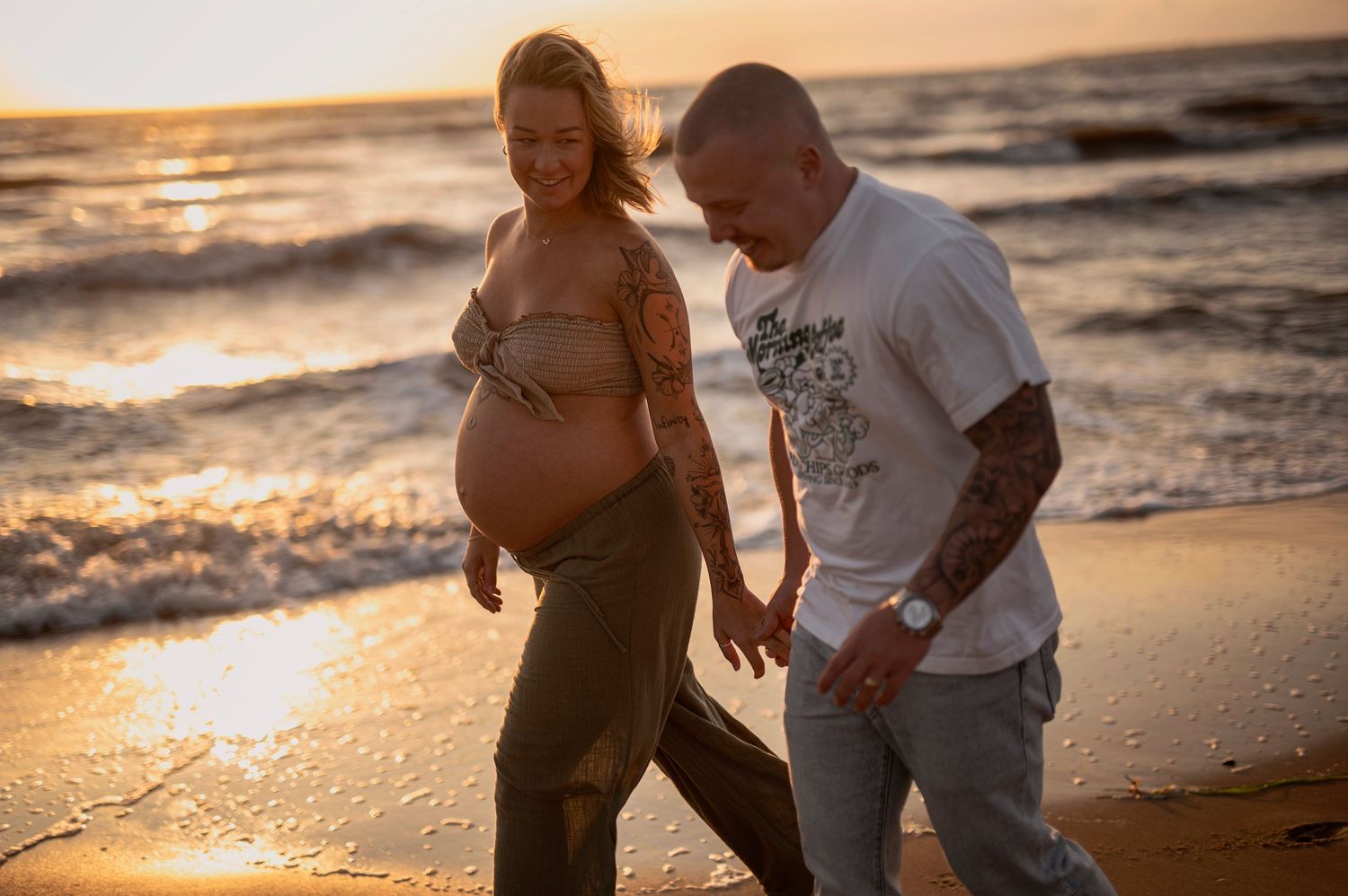 A couple enjoys a romantic sunset stroll along the shoreline of a tropical beach.