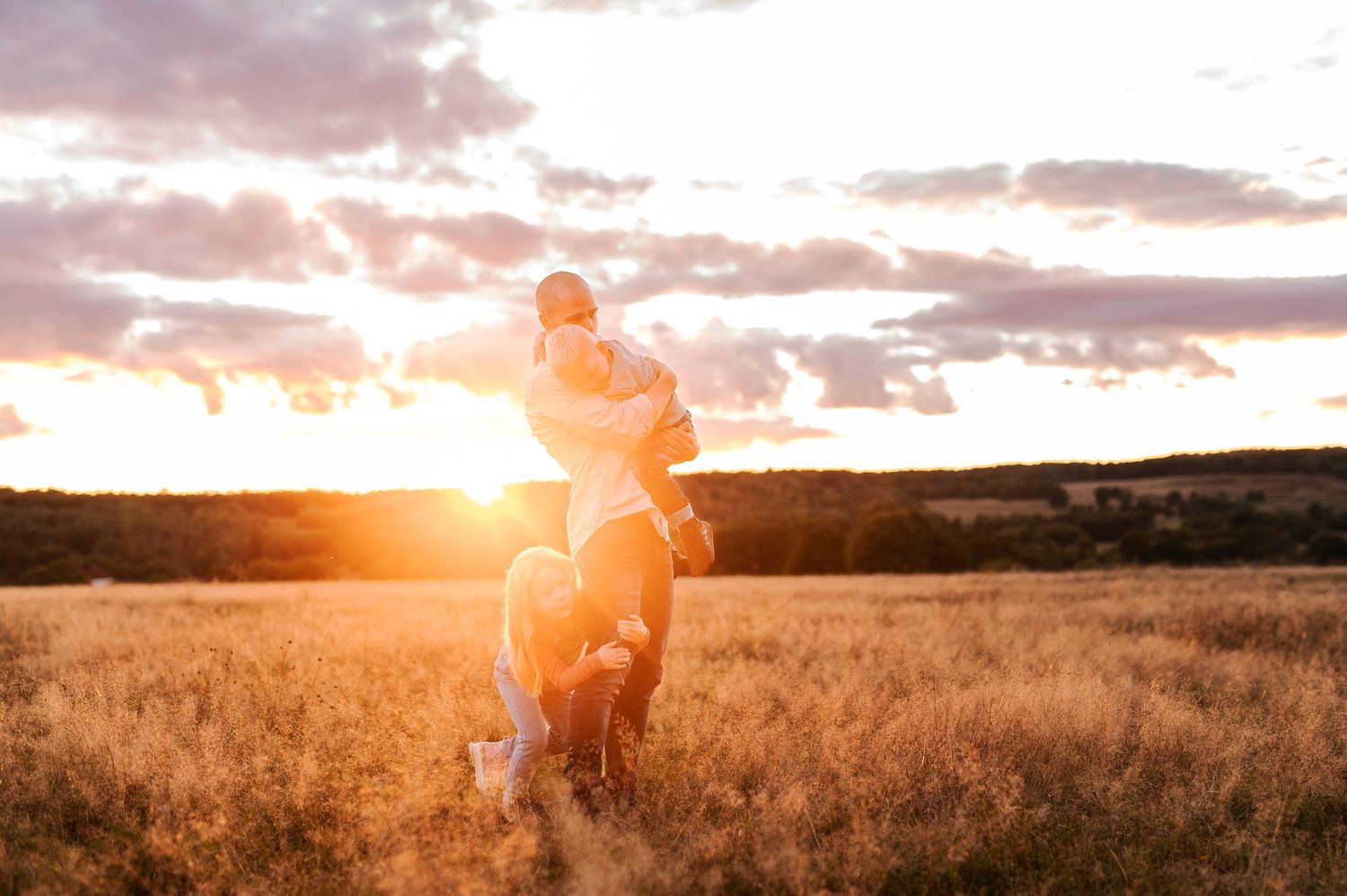 Silhouettes of family members playing in a field at sunset.