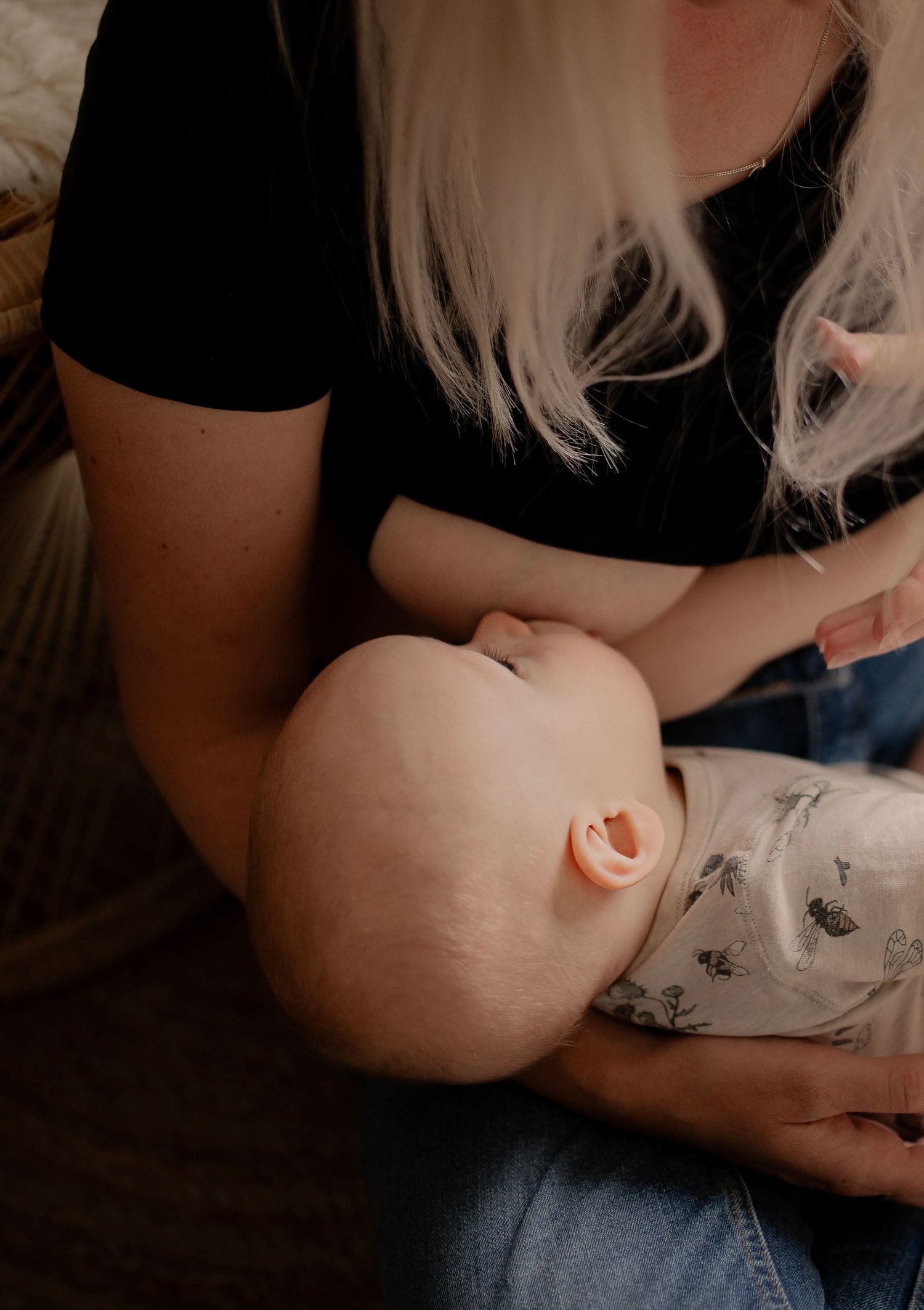 Close-up shot of a sleeping infant in a patterned onesie during a tender moment.