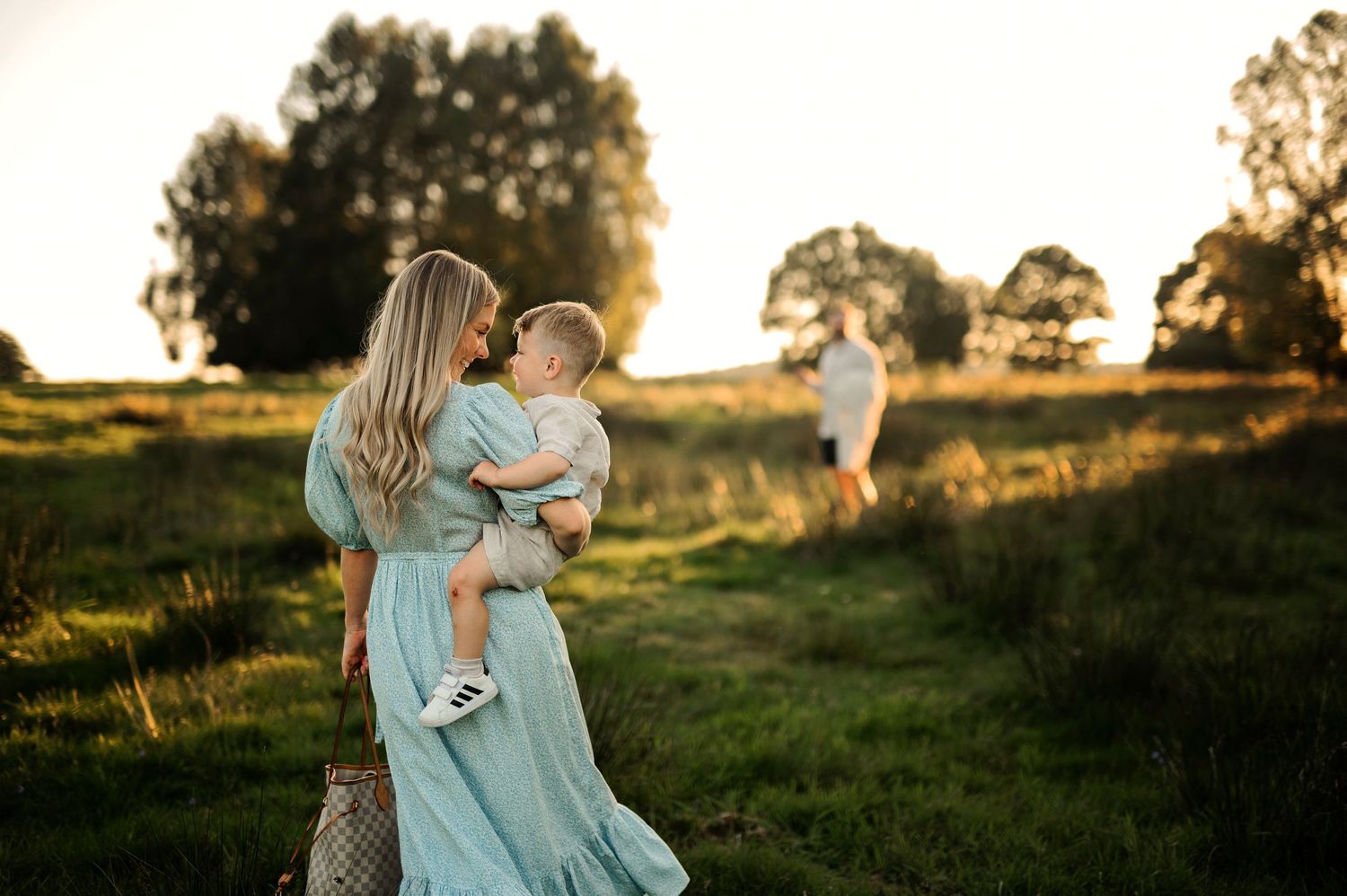 A gentle moment captured at sunset in a field with a person holding a small child.