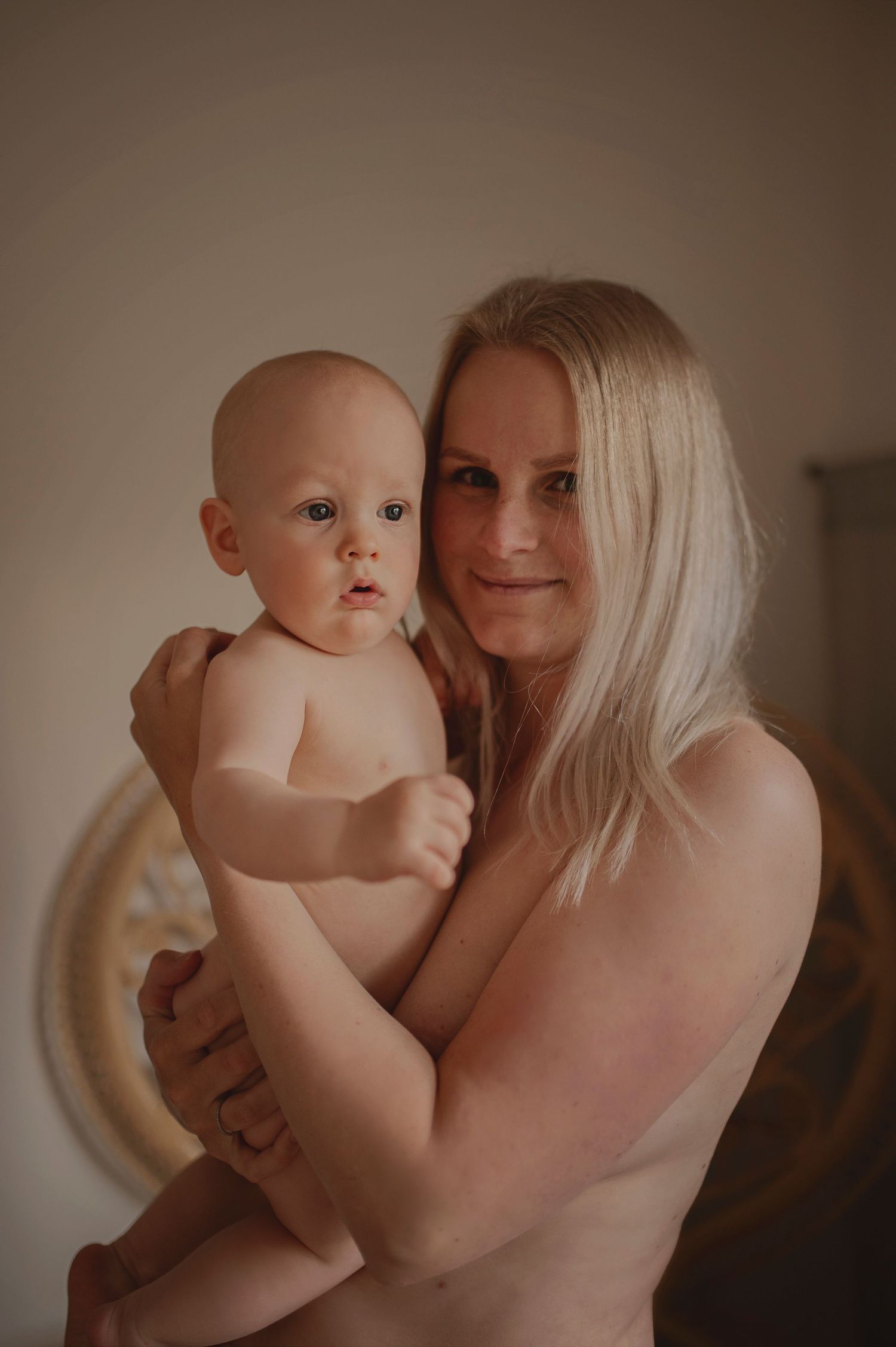 Artistic portrait of mother holding baby in soft, muted tones.
