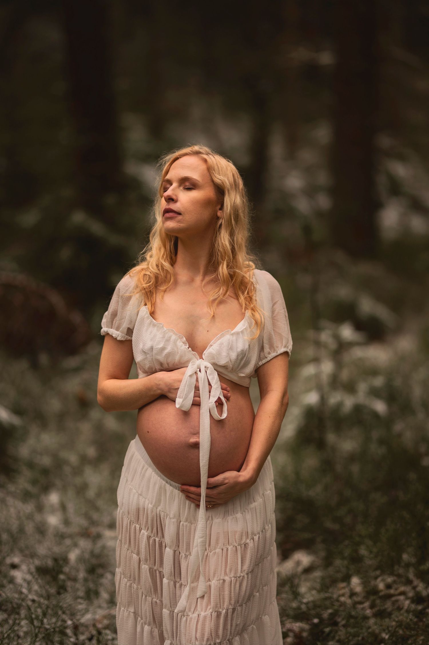 Vacker gravid kvinna på fotografering i en skog med mossa. Fotograf är Lovestories By Sara.