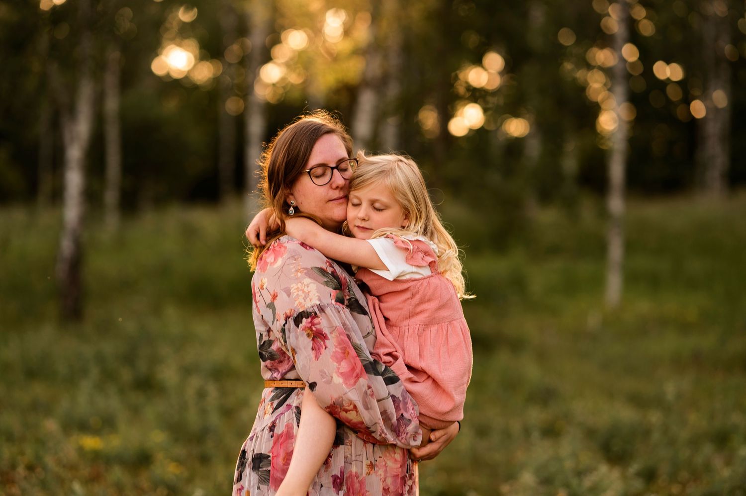Warm embrace captured in a floral dress amid birch trees at golden hour.