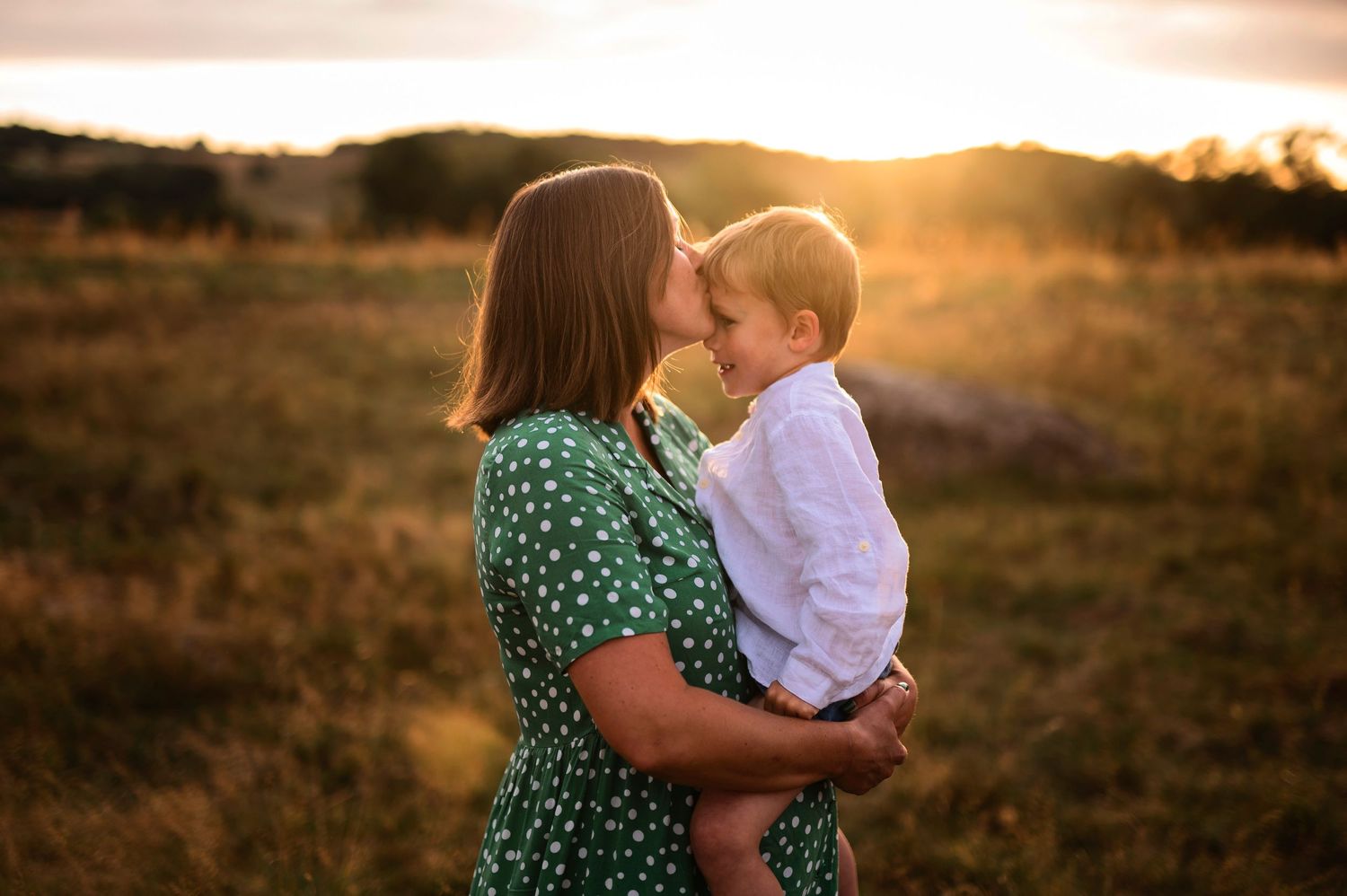 A tender sunset moment in a field with a green polka dot dress.