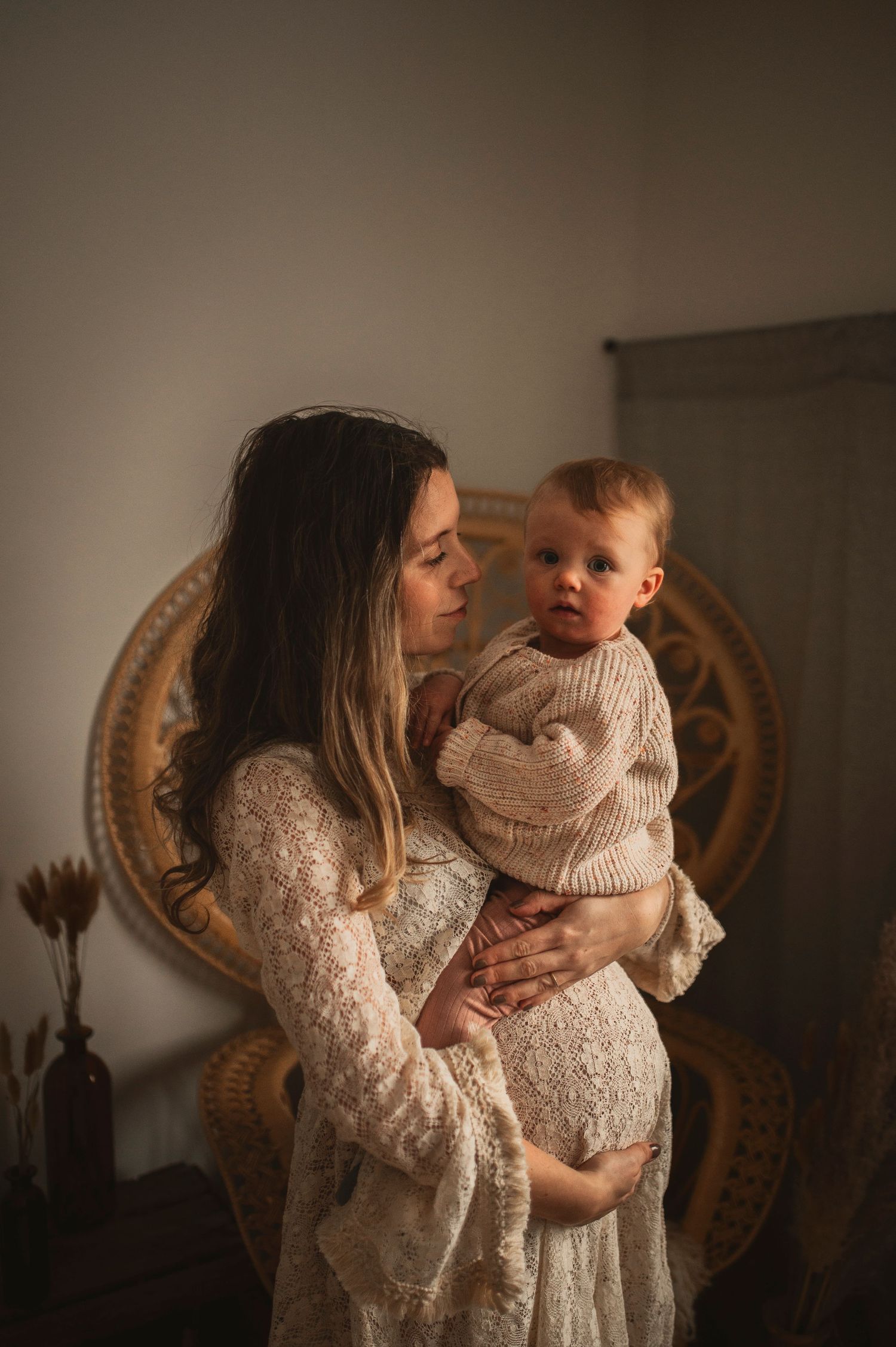 Intimate portrait of mother and baby in matching neutral tones against vintage decor.