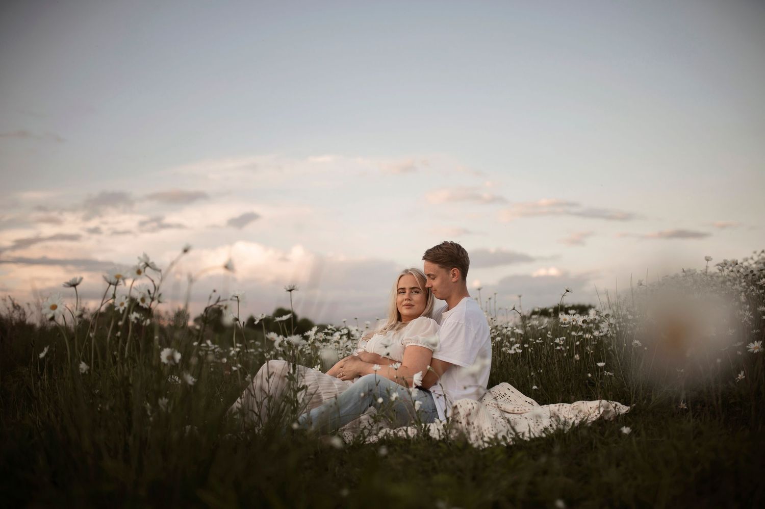 Artistic maternity portrait with vignette effect showing couple in field at twilight.