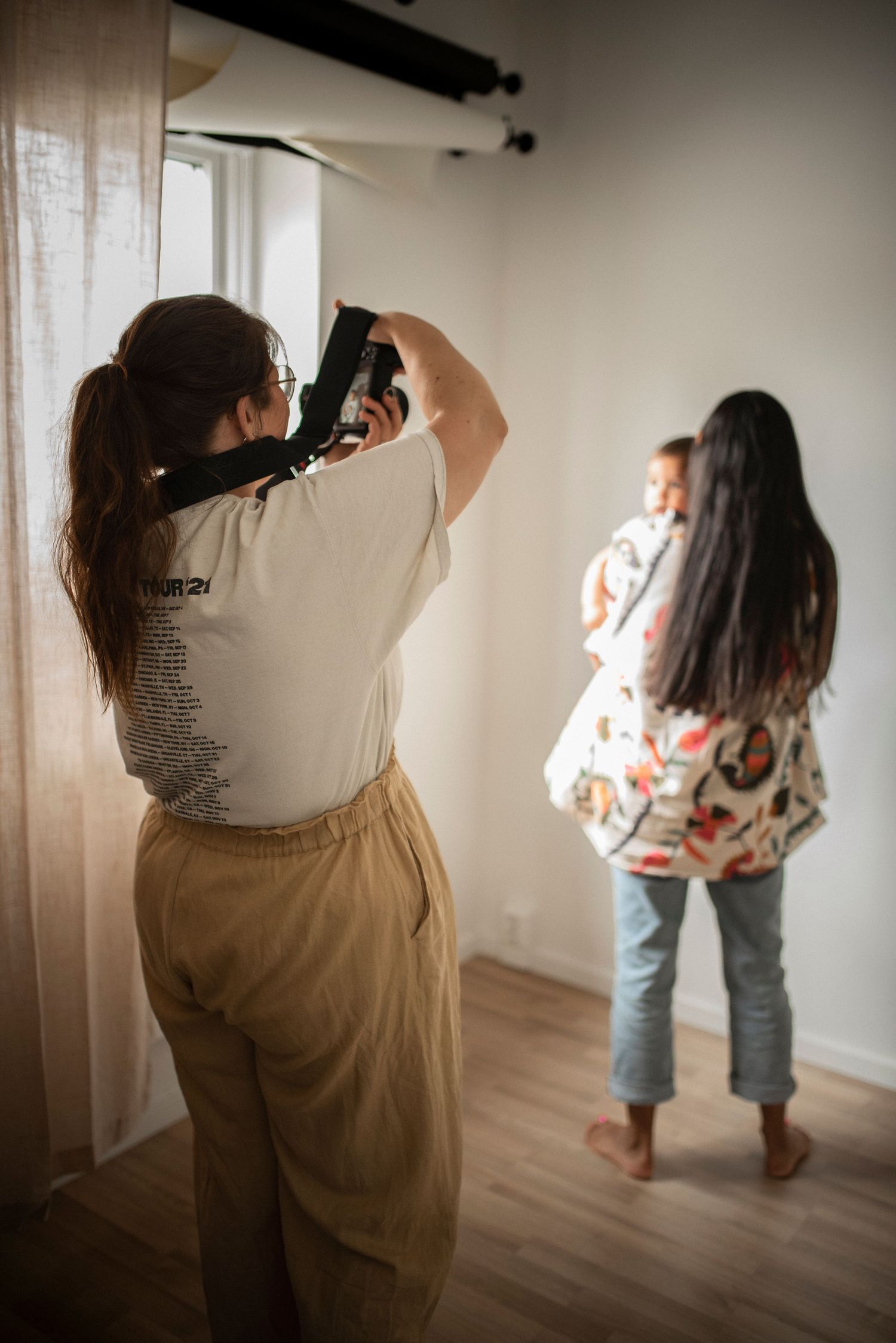 Photographer capturing mother holding baby in a bright indoor photography studio session.