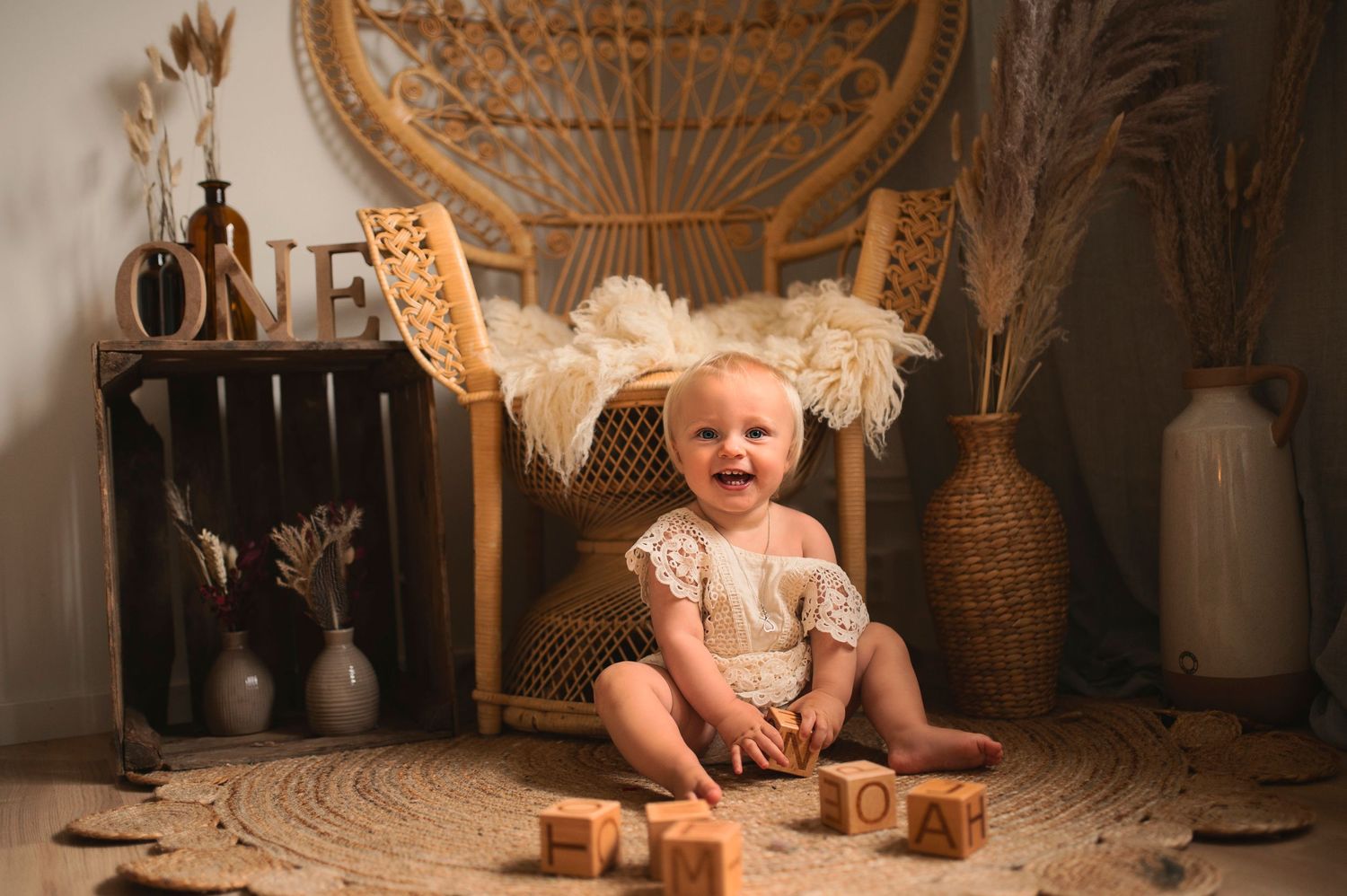 Vintage-inspired first birthday setup with peacock chair, wooden blocks, and boho decorations.