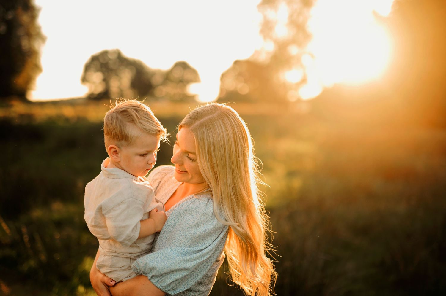 A warm sunset moment captured between two people in a grassy field.