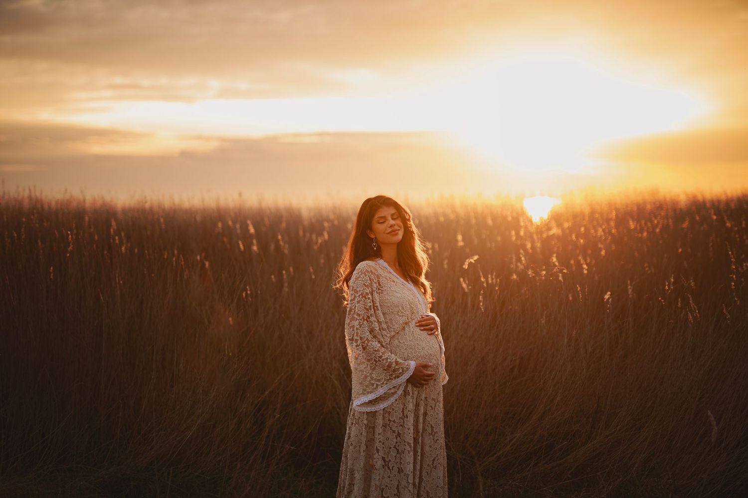 Dreamy sunset maternity portrait in a golden wheat field.