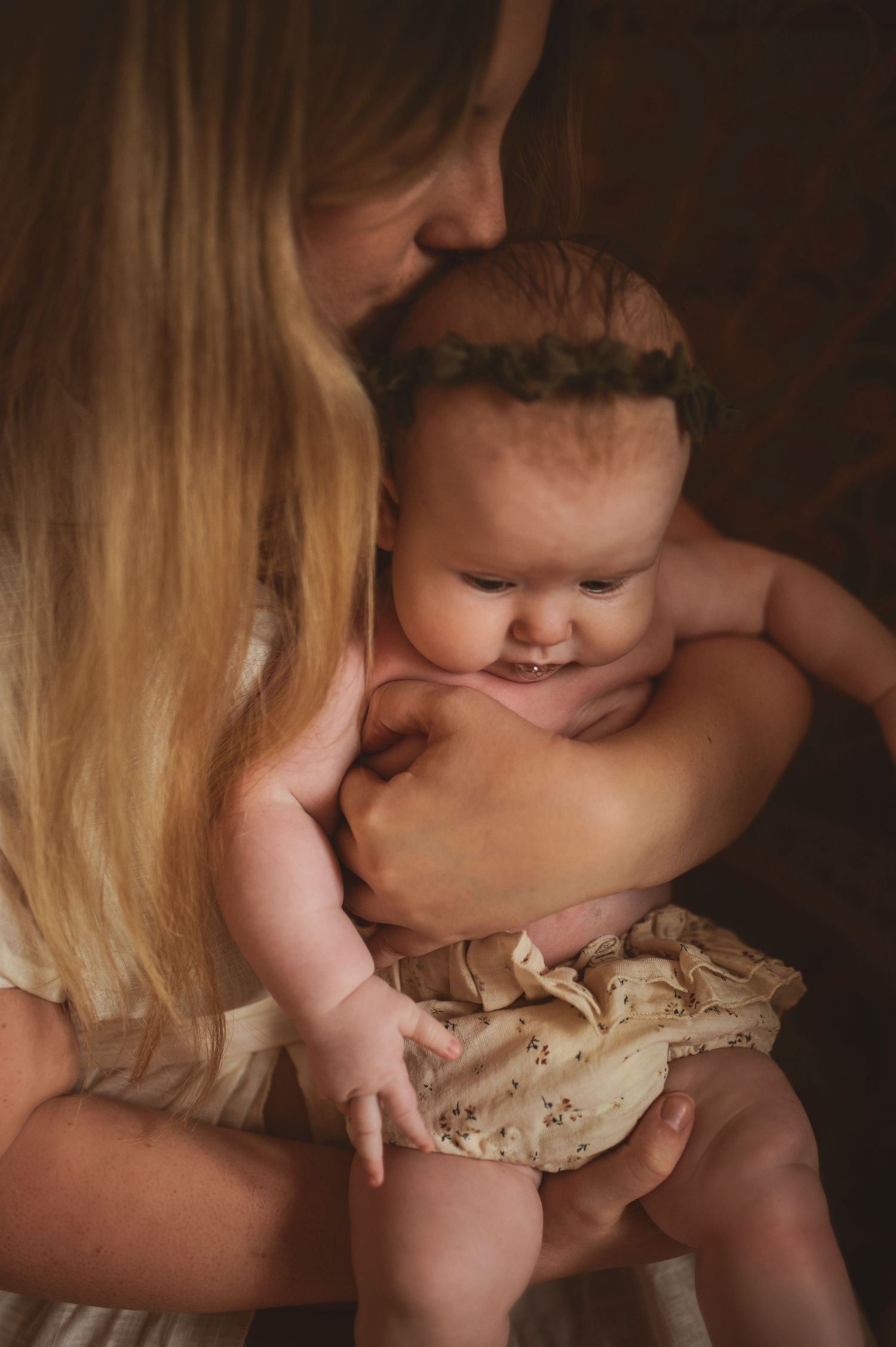 Intimate moment between mother and baby in soft lighting.