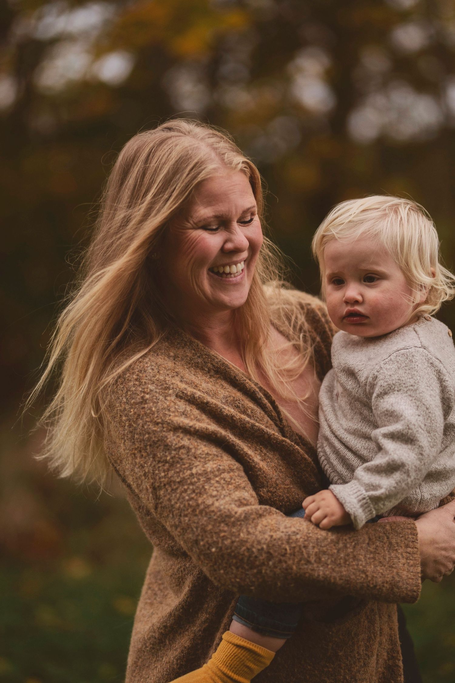 A heartwarming moment of bonding between adult and child wearing cozy sweaters on an autumn day.
