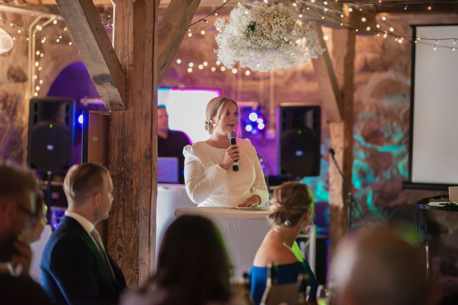 A reception venue decorated with string lights and wooden beams creates a cozy atmosphere.