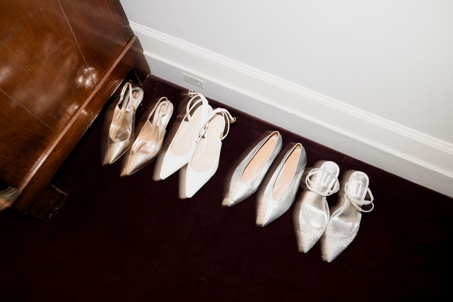 A series of white ballet pointe shoes arranged in a row along a white wall shelf. Paris wedding photographer