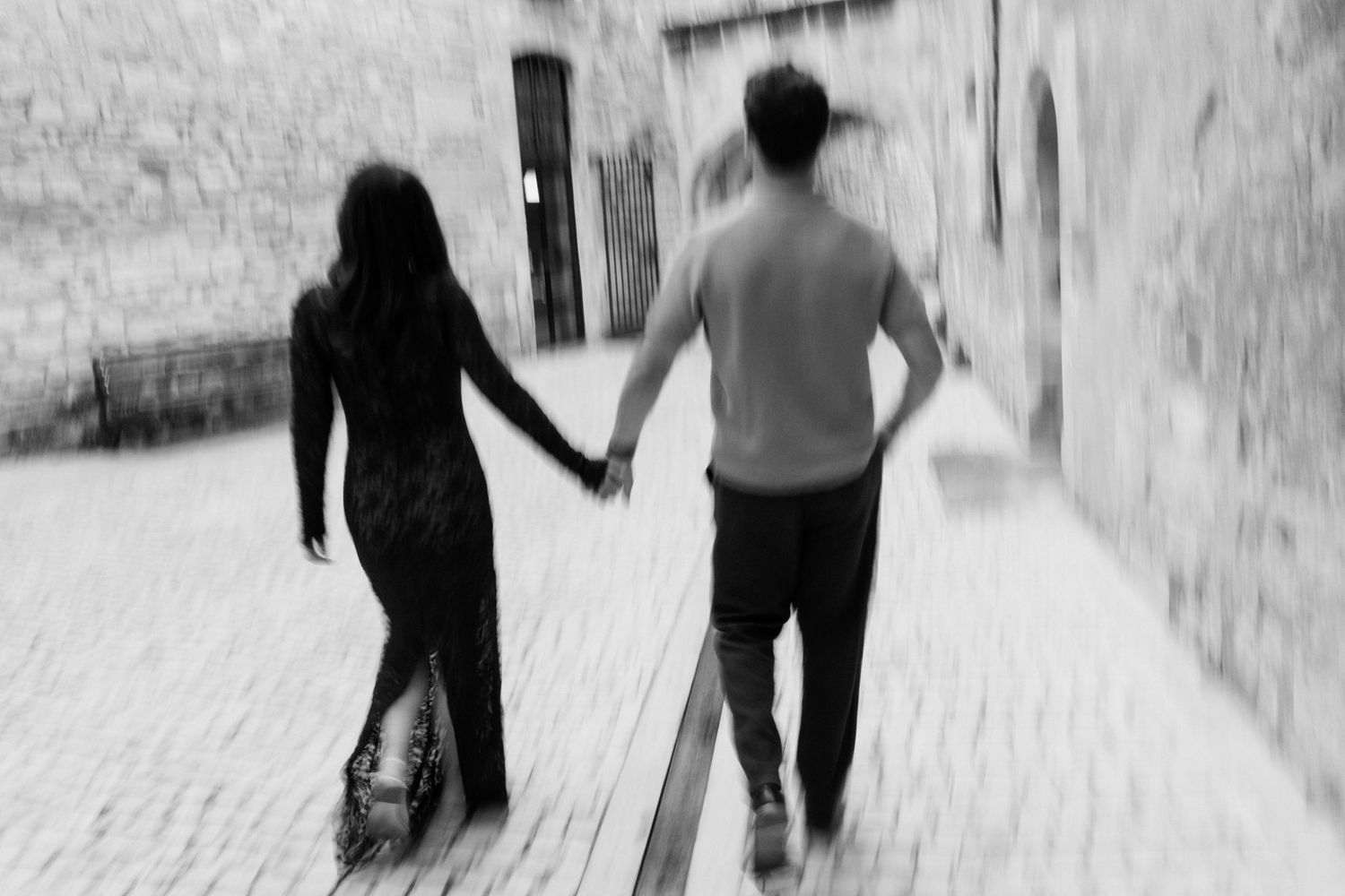 Two people holding hands walk down a snowy path in black and white photography. Saint Remy de Provence