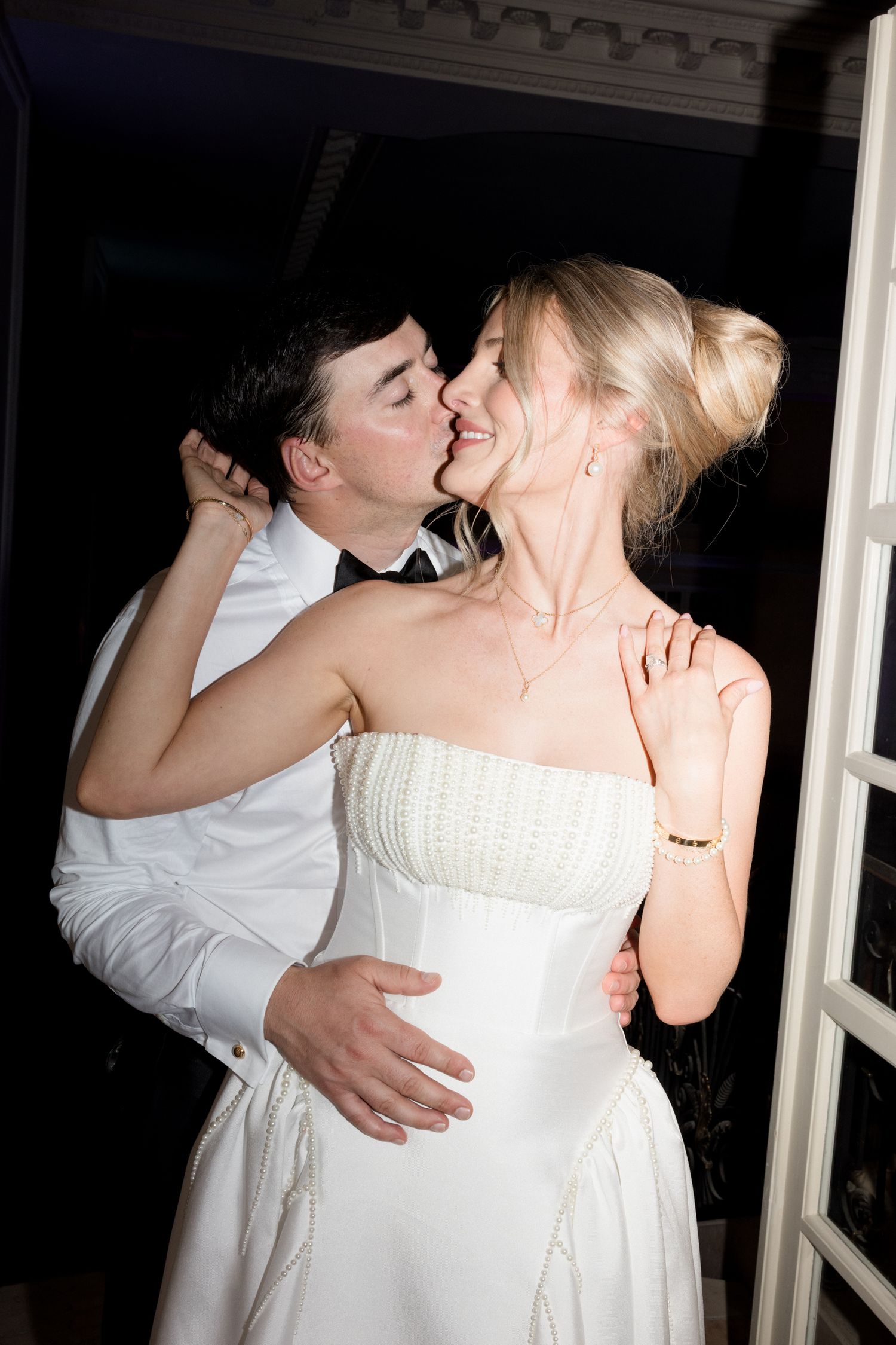 A romantic moment between newlyweds sharing a kiss while dressed in formal white wedding attire. Photographe mariage france luxe