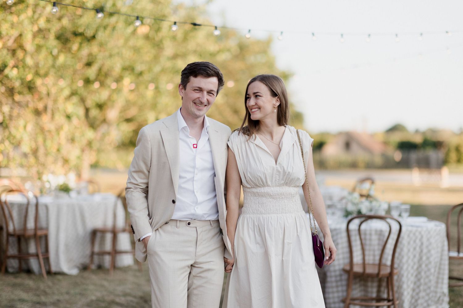 A couple in light beige and cream attire pose together during a romantic outdoor wedding celebration at sunset. Photographe mariage Tours