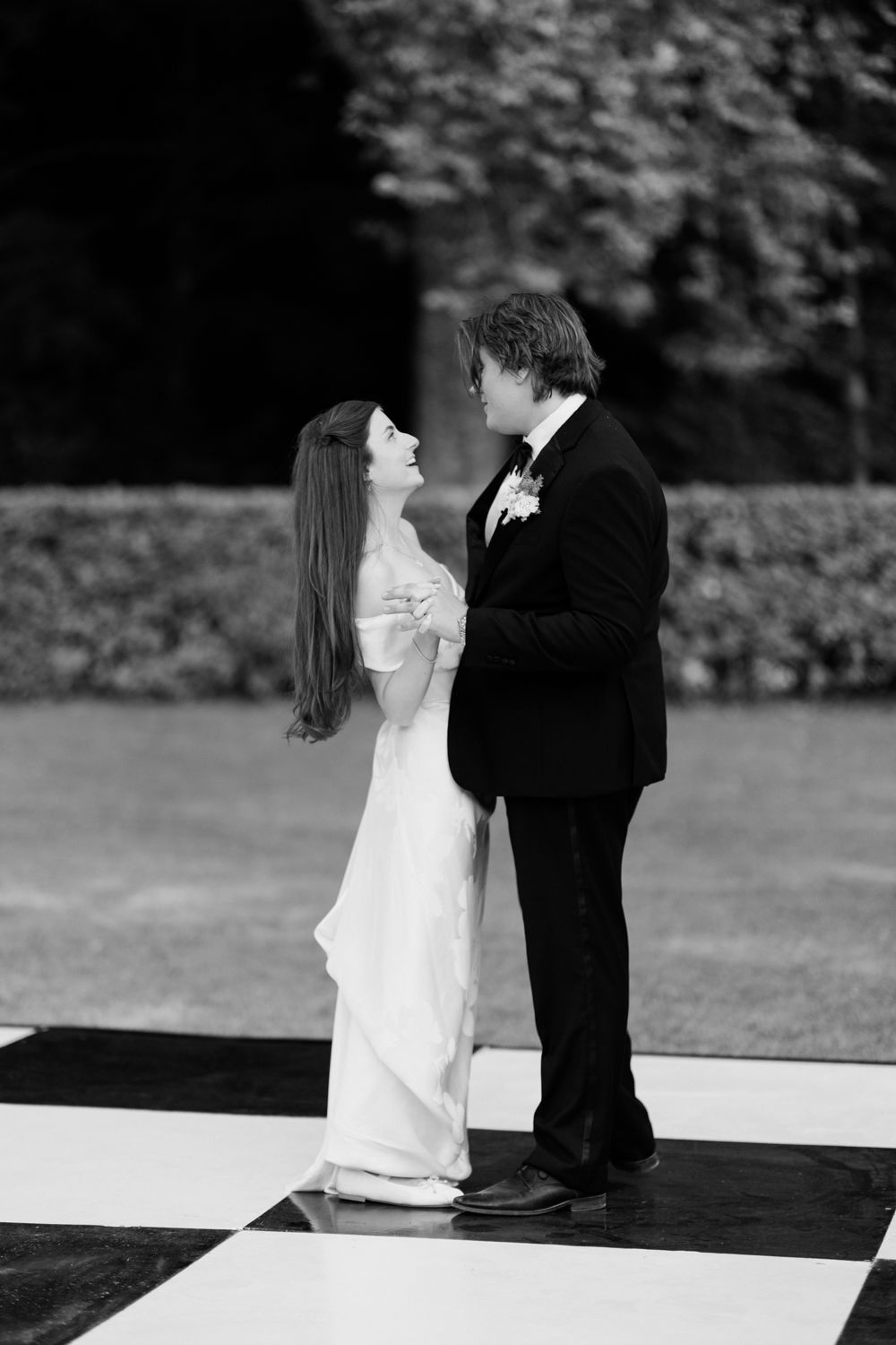 A lovely couple in formal wedding attire share an intimate moment together on a black and white deck.