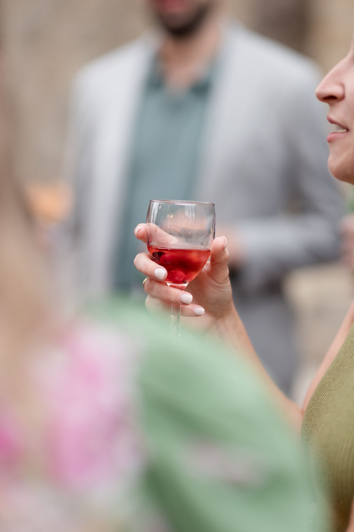Several hands hold glasses of red wine in a social gathering setting against a blurred background.