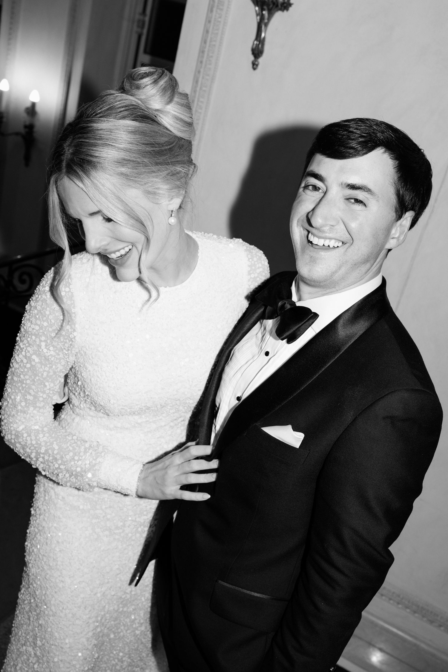 Black and white wedding photos show intimate moments between bride in lace dress and groom in tuxedo during reception. luxe wed france