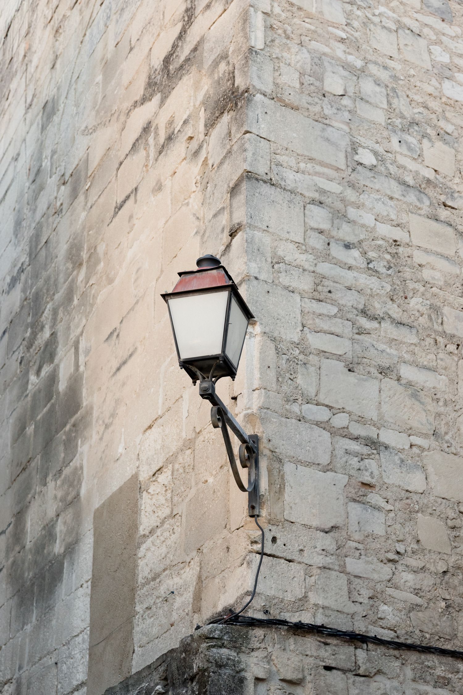 A vintage-style wall lantern mounted on a weathered stone wall.