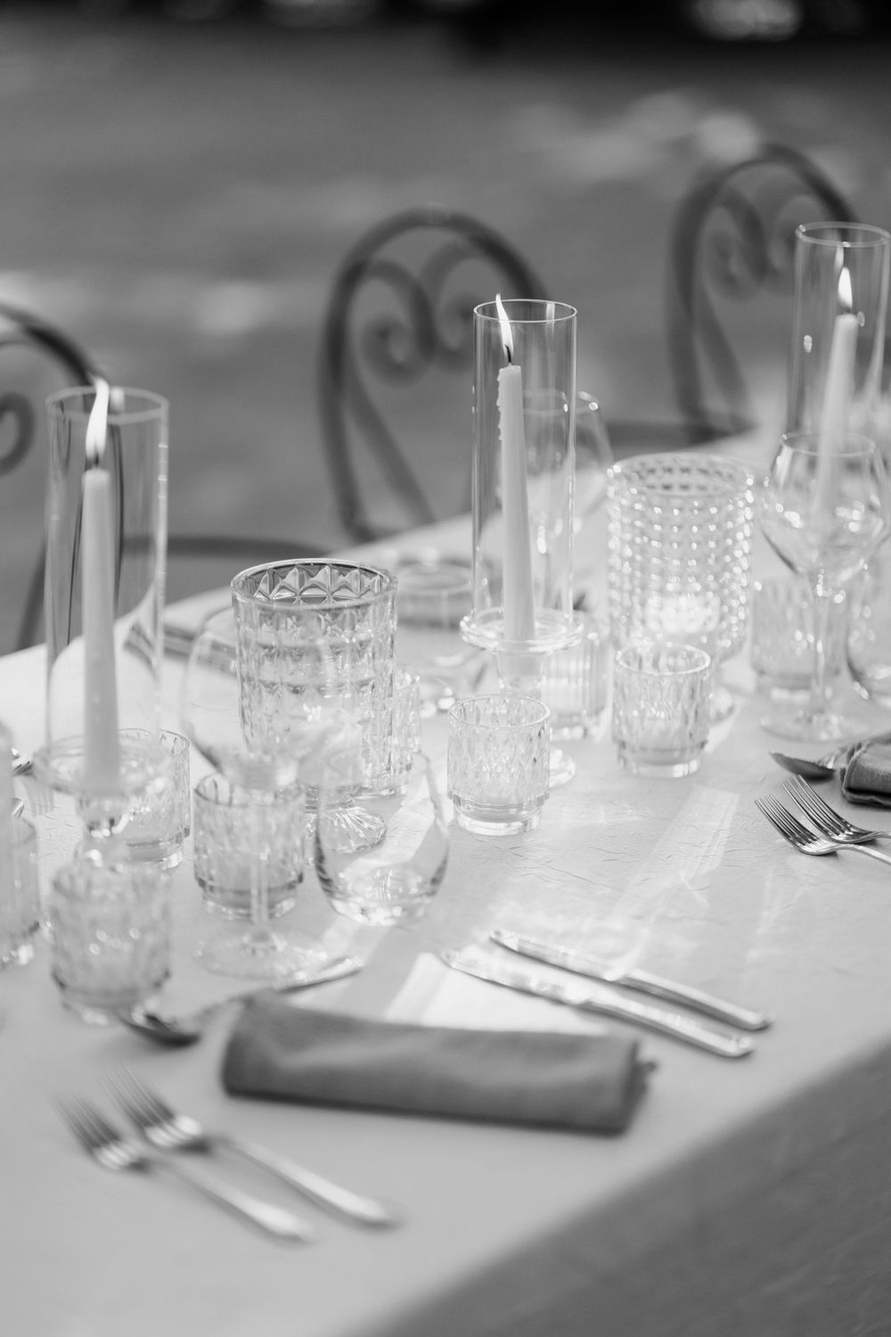 Elegant table setting with crystal glassware and cutlery arranged on white linen in black and white photography. Auberge de la Treille
