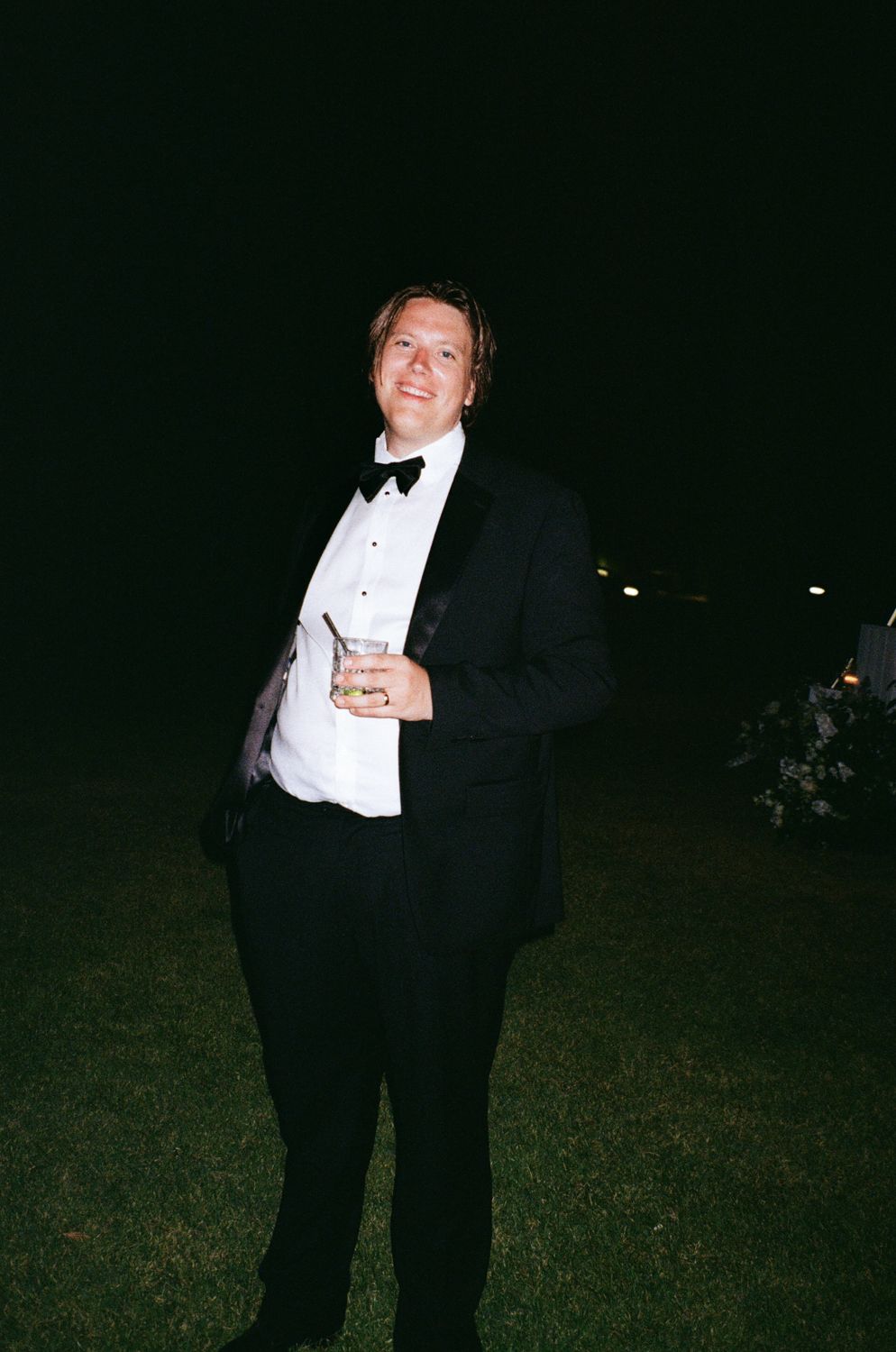 Four sequential nighttime photos show someone in formal attire striking dramatic poses outdoors in the dark.