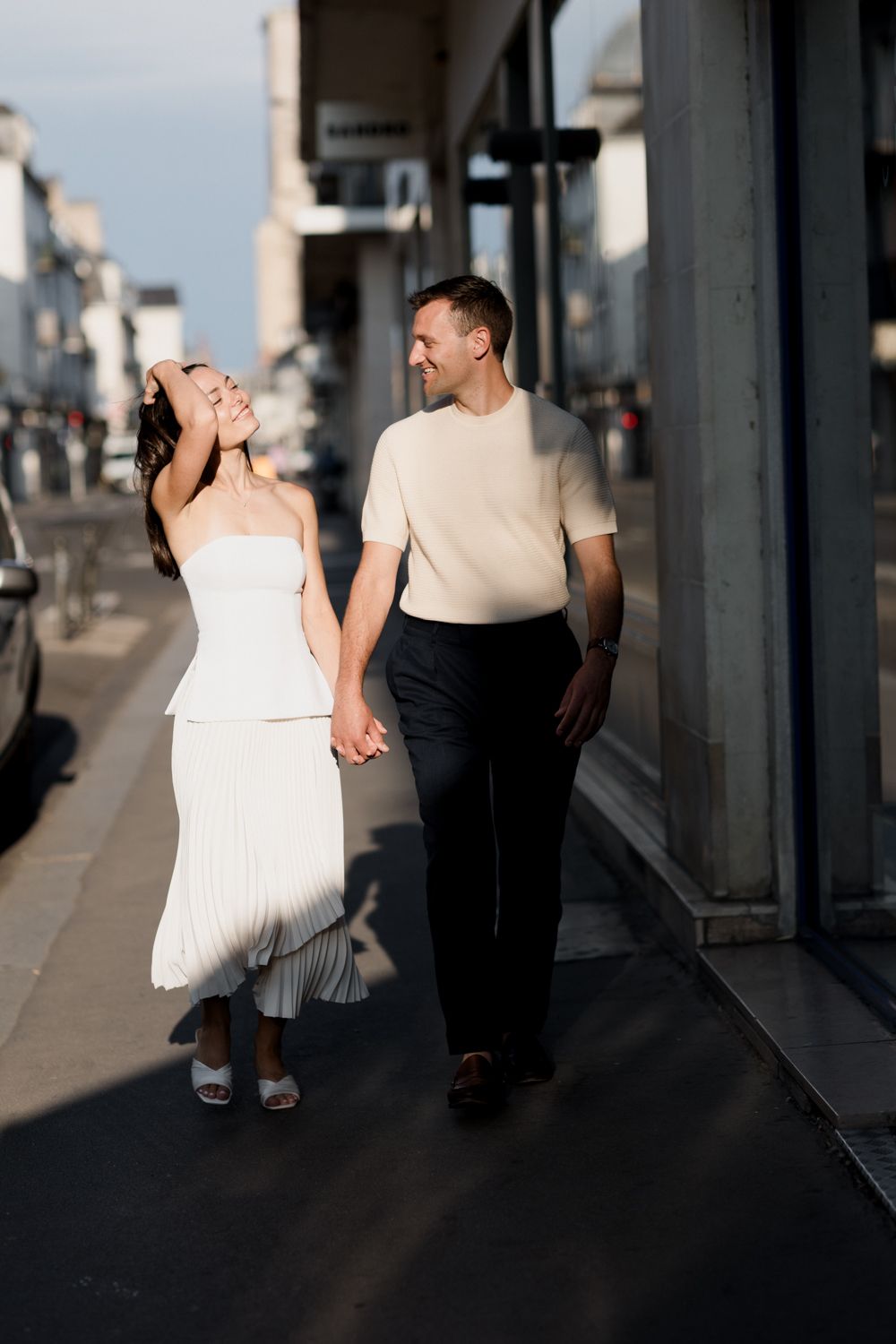 Couple walking together down a covered walkway with columns casting dramatic shadows.