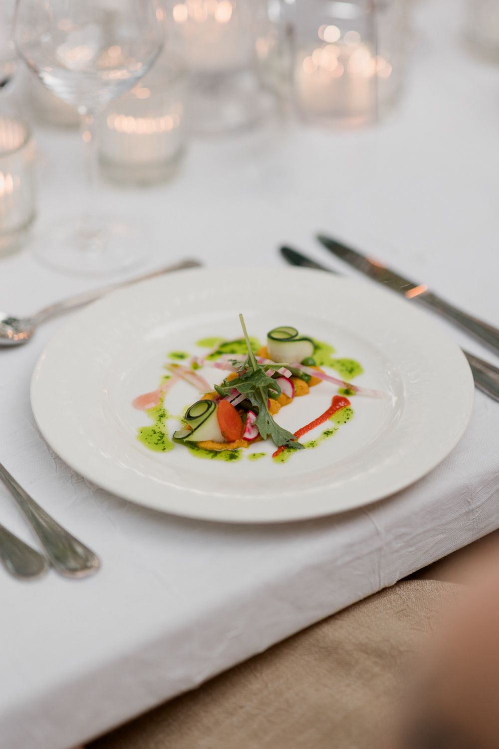 Elegant plated appetizer with smoked salmon, microgreens and sauce on white china at upscale restaurant table setting.