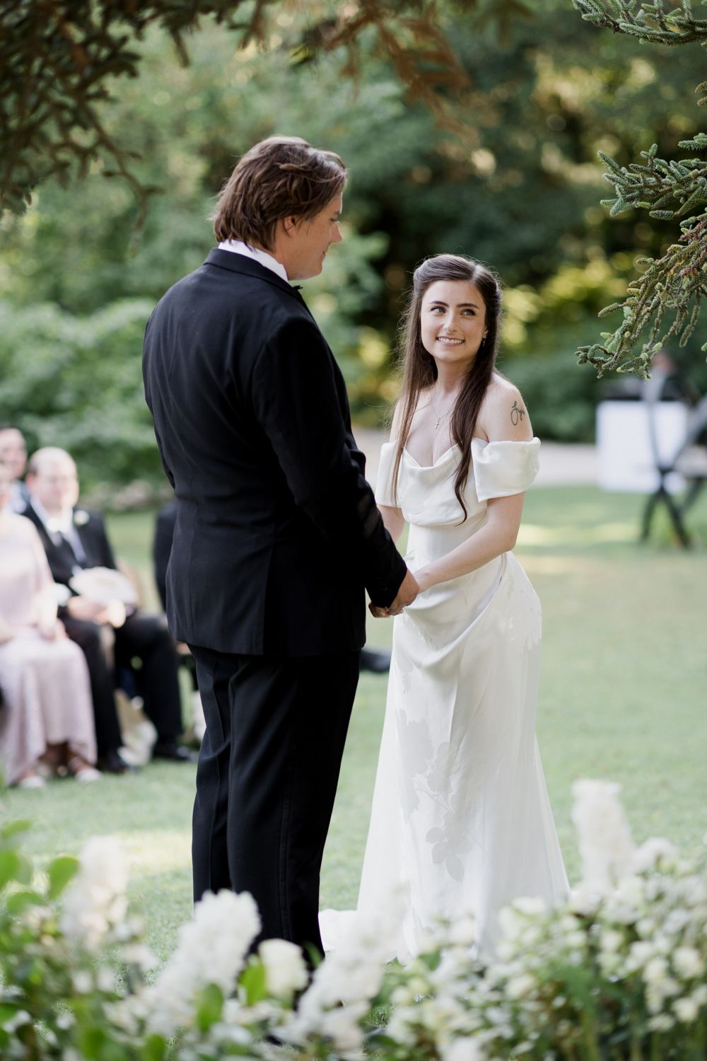 A romantic outdoor wedding ceremony with a couple exchanging vows surrounded by greenery and garden flowers.