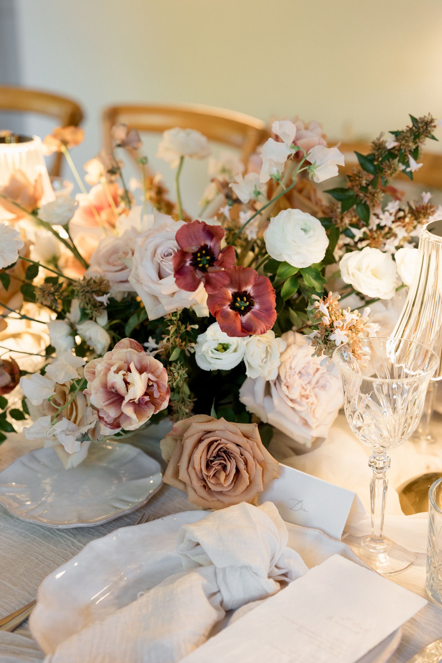 Elegant table setting with blush roses, white flowers and crystal glassware in soft natural lighting. wedding photographer france