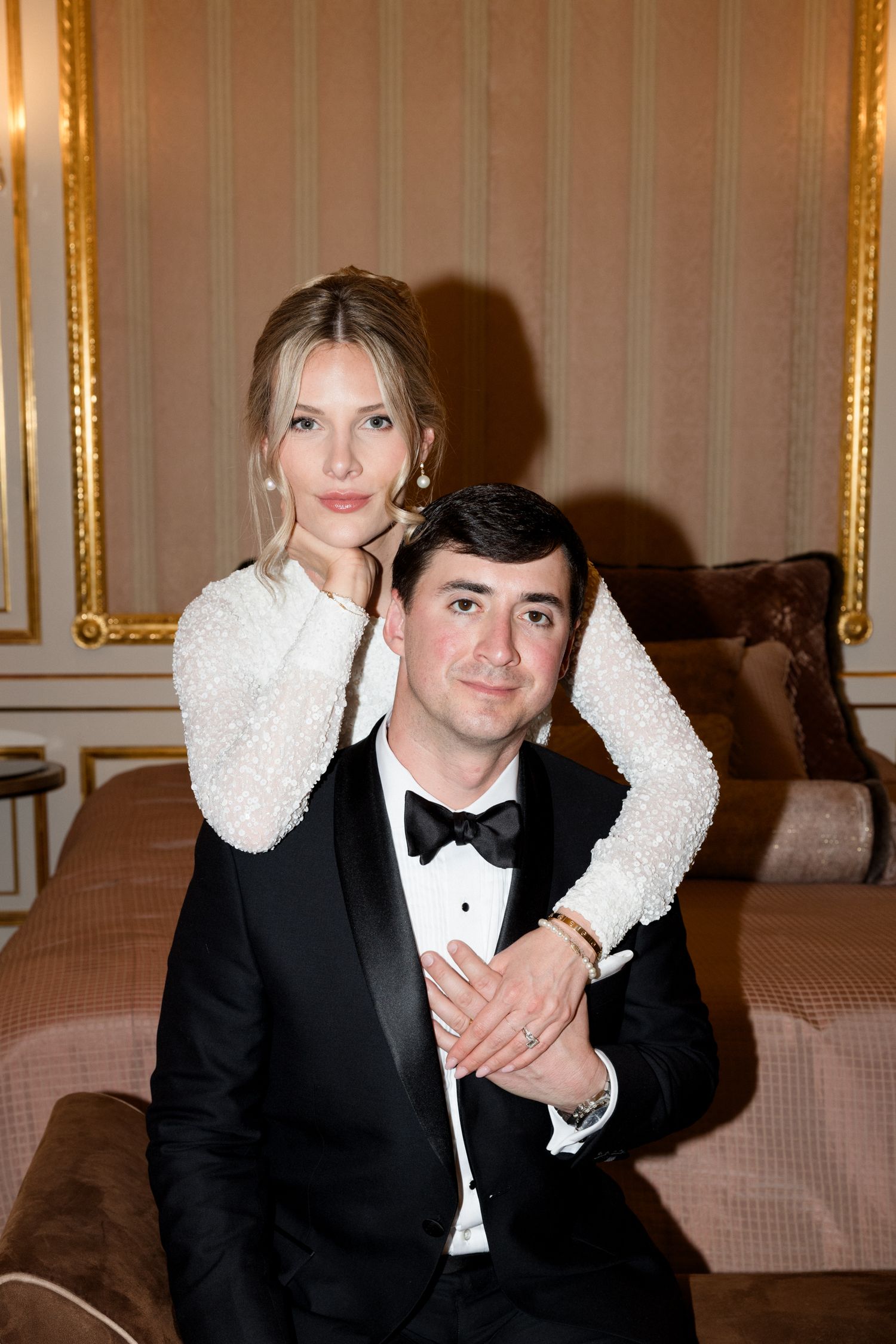 Two people in formal attire pose together at an elegant event with gold-framed artwork visible in the background. Mariage Grasse France