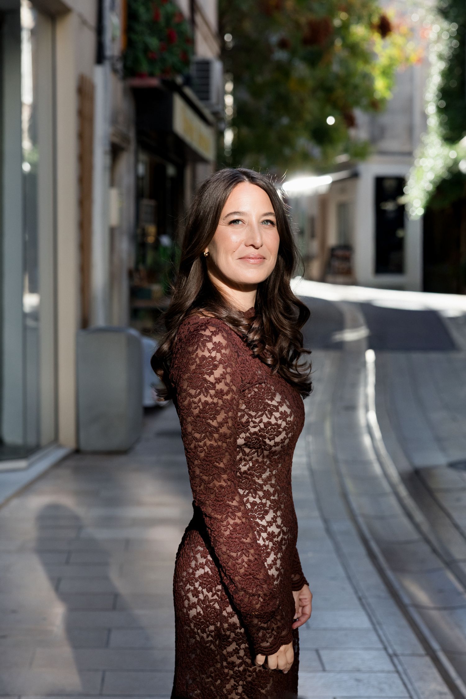 A woman in a sparkly brown sequin dress poses confidently on a city street in five sequential photos.