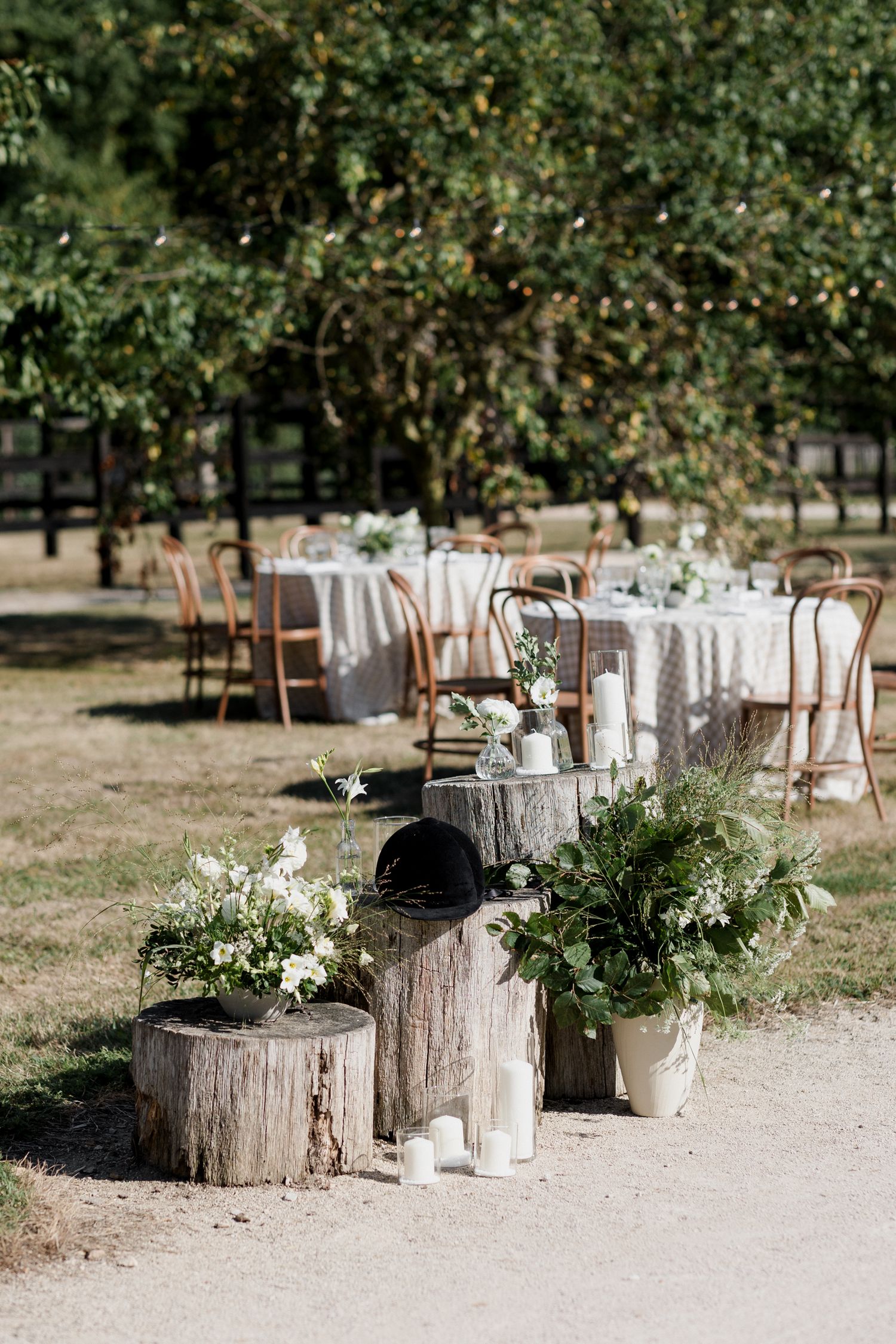 Rustic wedding decor featuring tree stumps with candles and greenery arranged in an outdoor garden setting.