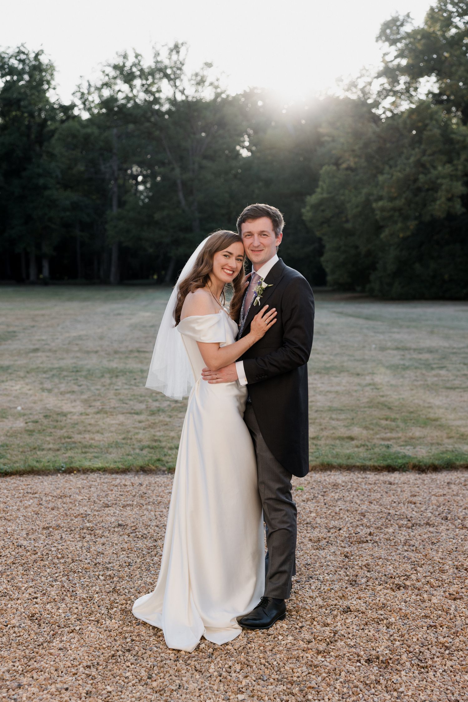 A romantic wedding couple shares a tender moment in a sun-drenched outdoor field at sunset. Paris wedding photographer