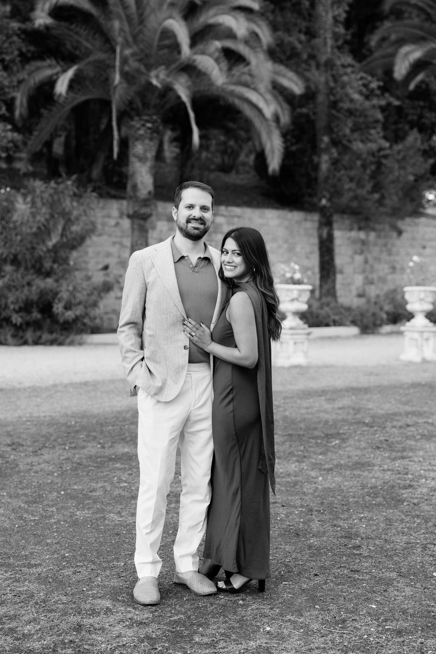 A couple stands together outdoors in black and white photos showing progression of their romantic moment.