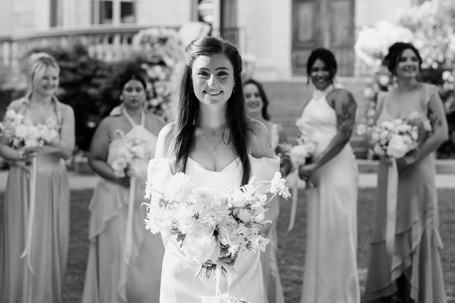 Bridesmaids wearing soft blue dresses smile together during wedding photo session outdoors.