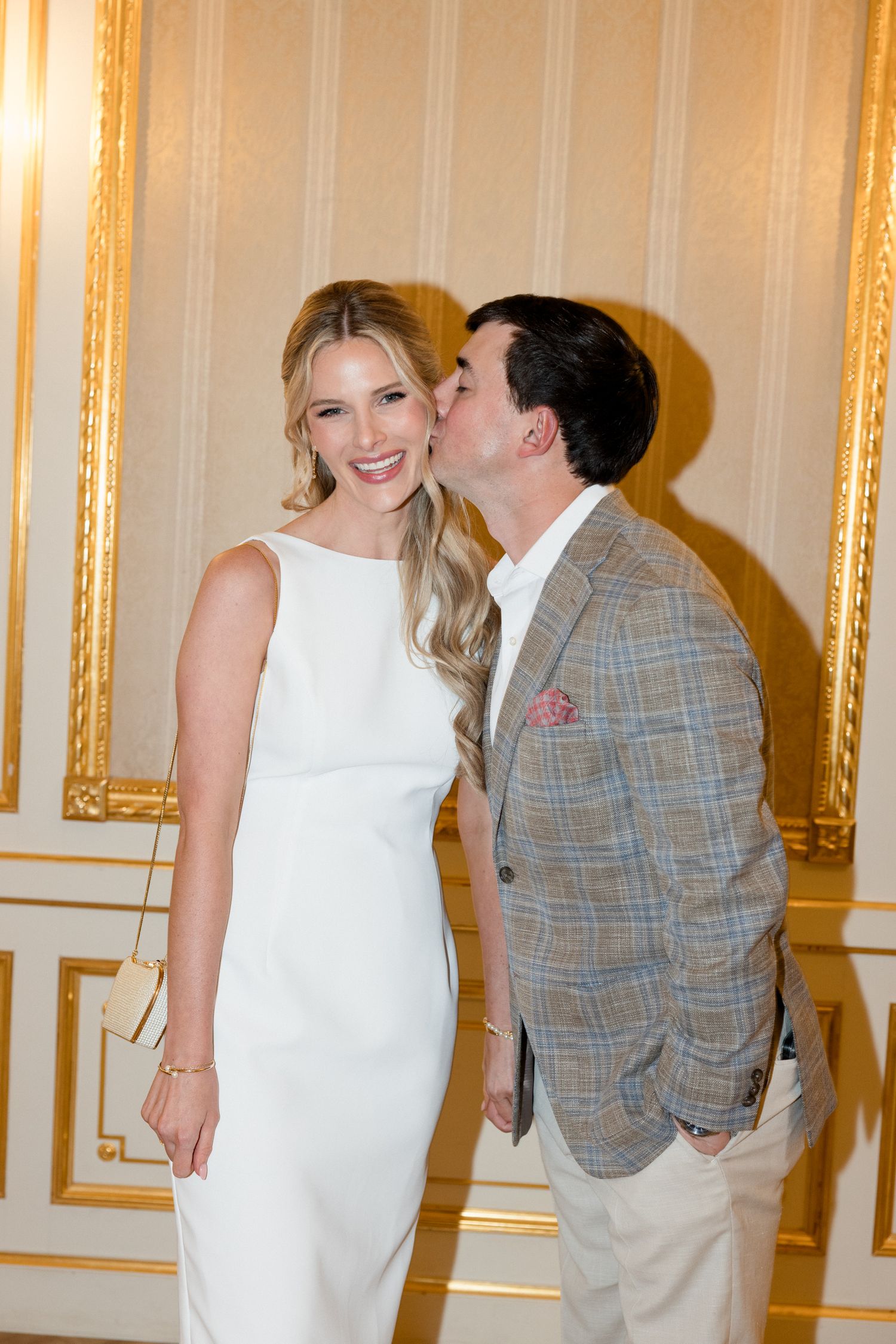 A couple shares a sweet moment in an elegant room with ornate gold-trimmed walls.