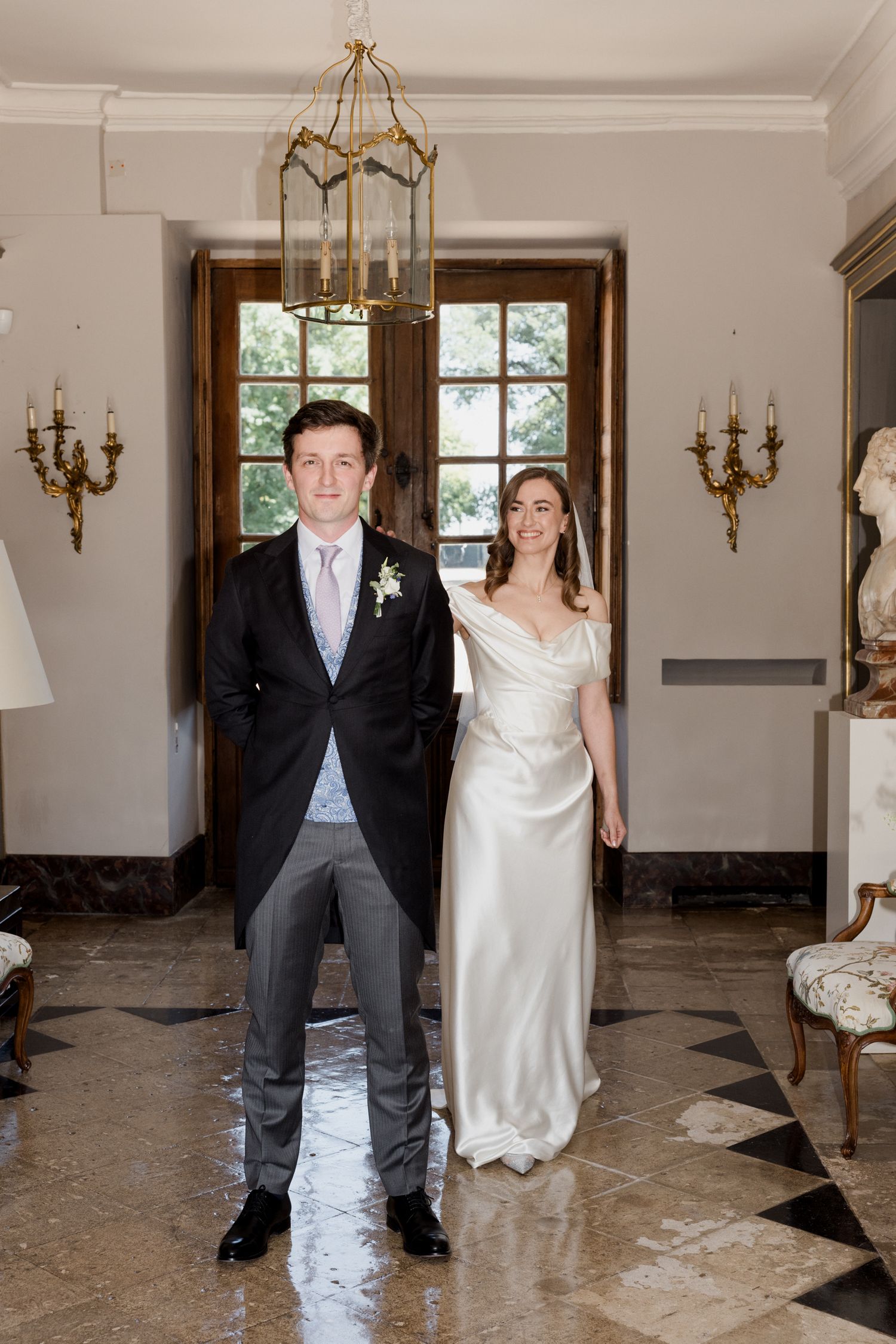 A couple in formal wedding attire performs a fun jumping dance sequence in an elegant room with chandeliers. Paris wedding photographer