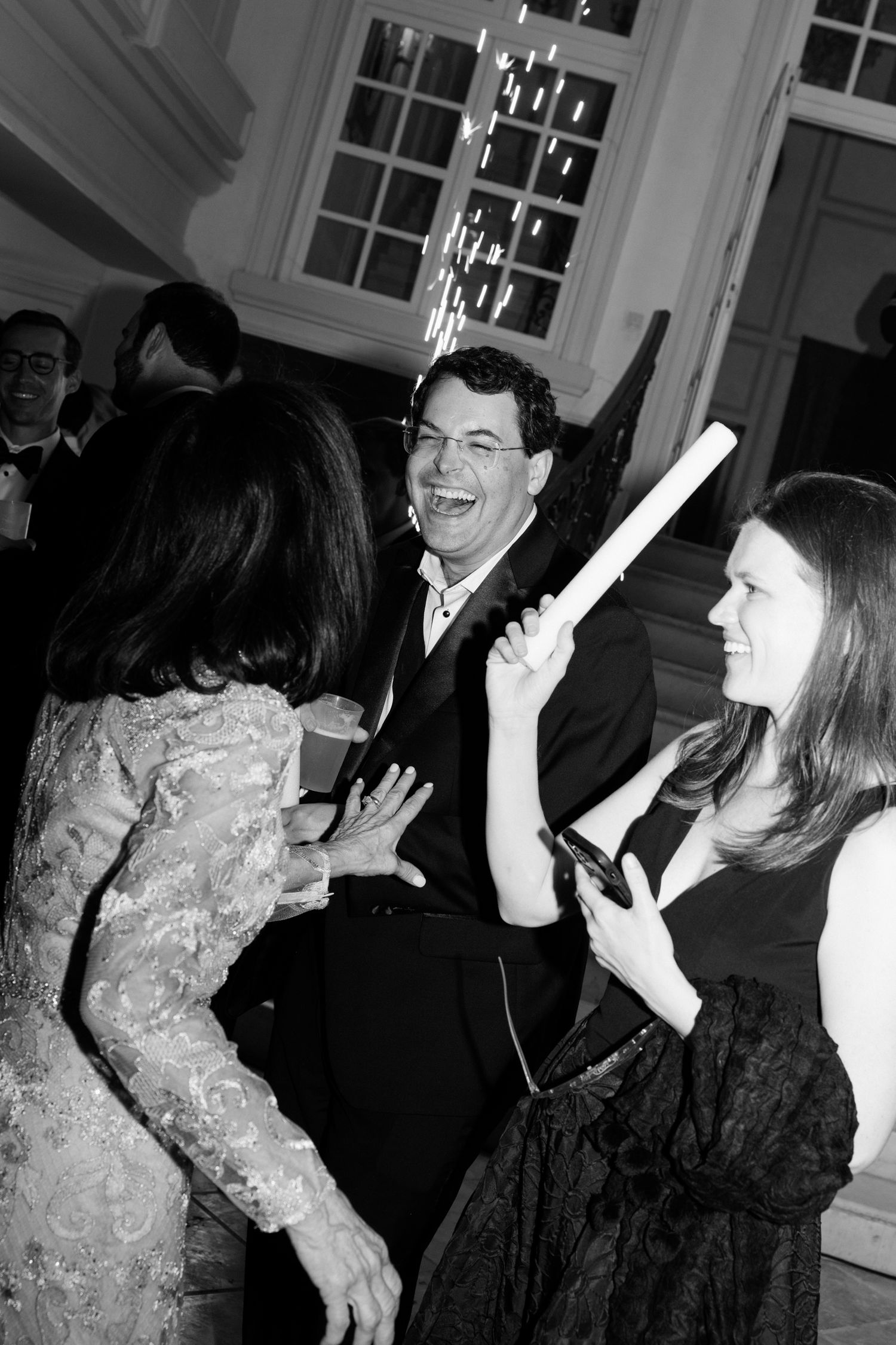 People dancing and celebrating at a formal party in black and white.