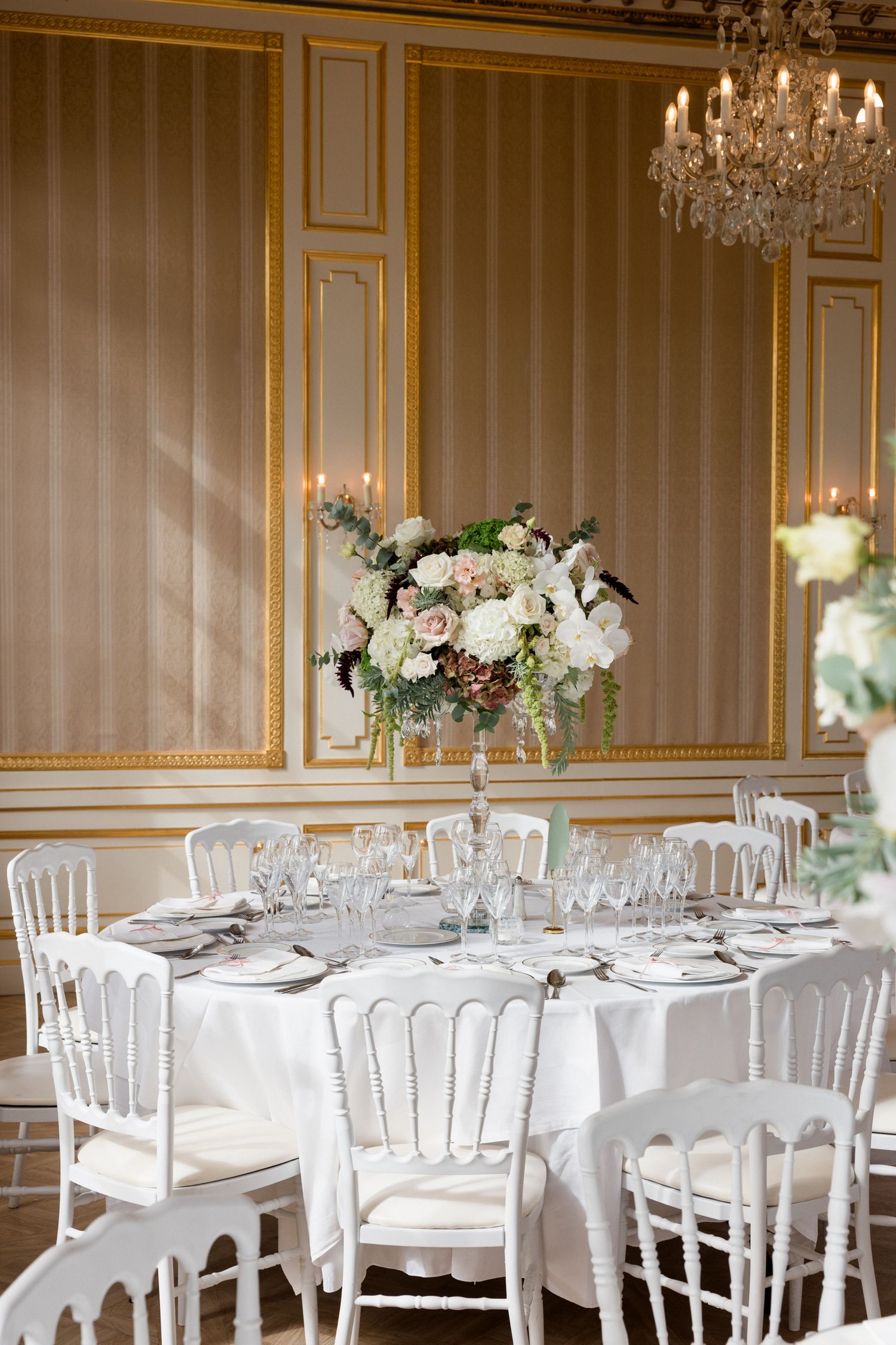 Elegant wedding reception tables with crystal chandeliers and white floral centerpieces in a luxurious French-style ballroom. grasse