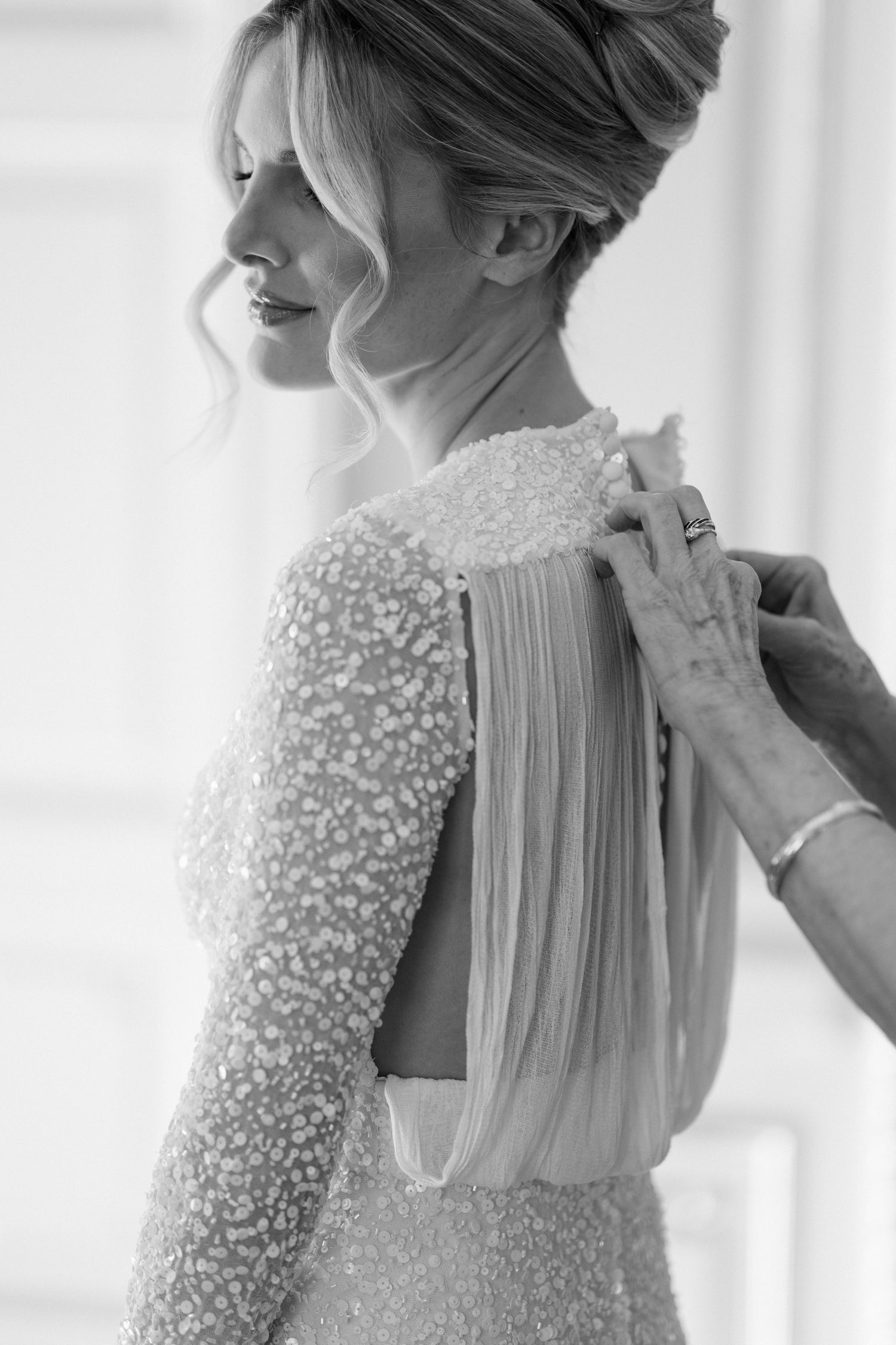 Close-up view of an elegant wedding dress with delicate beaded details and sheer fabric panels in soft natural light.