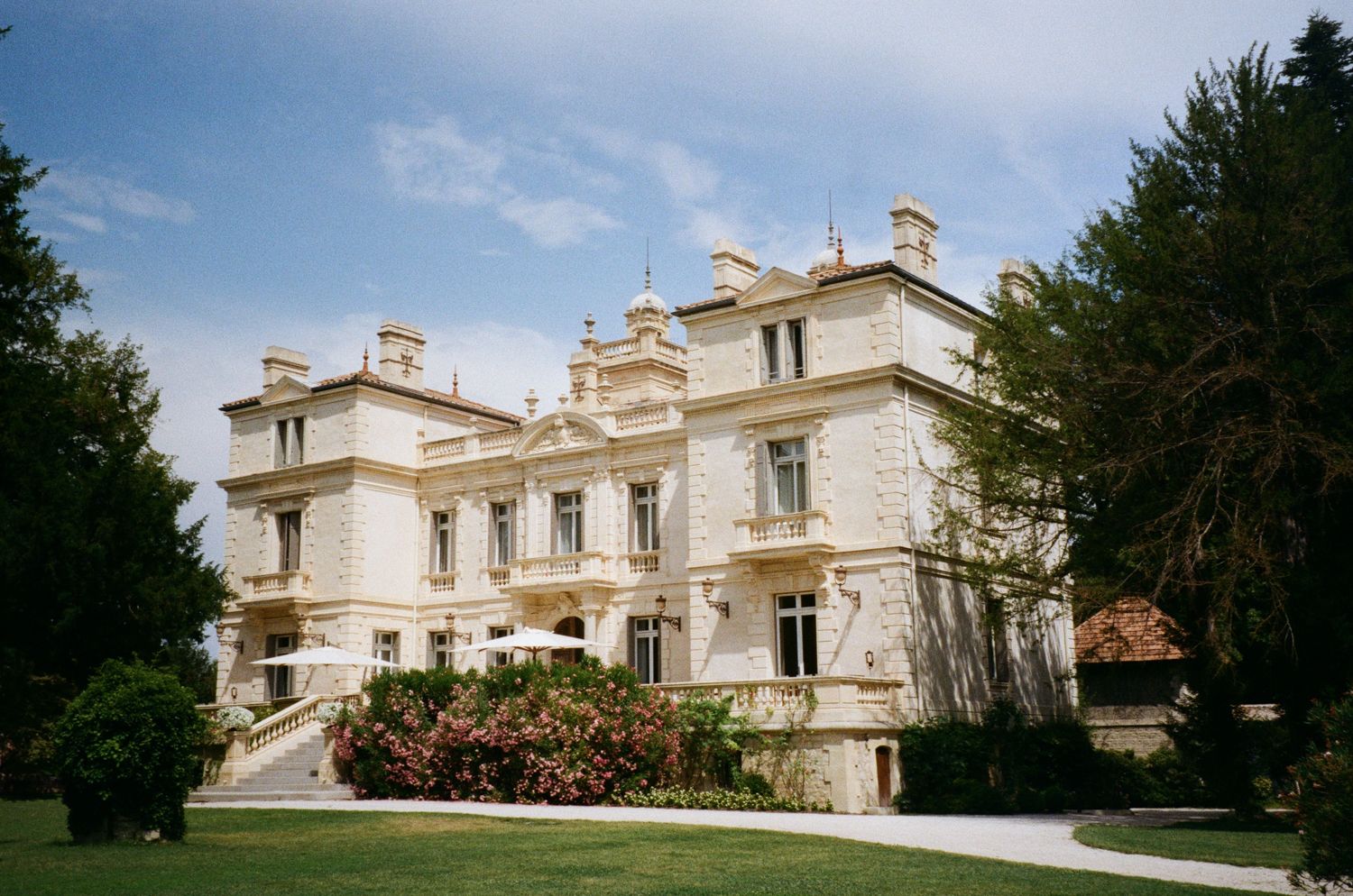 Grand white Victorian mansion with ornate architectural details and symmetrical design stands elegantly on manicured grounds.