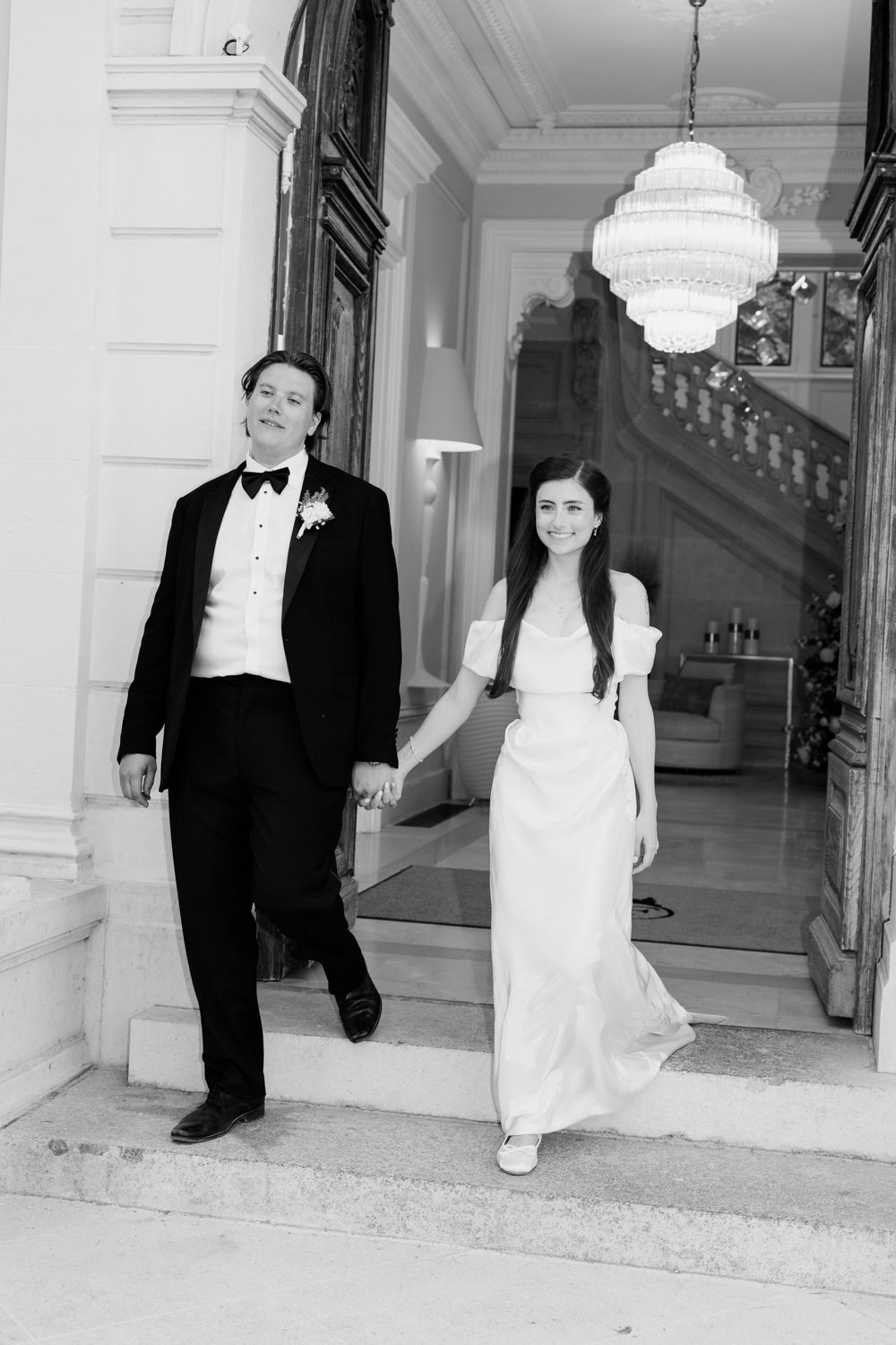 A black and white photo collage showing a wedding couple posing in an elegant building hallway with white pillars.