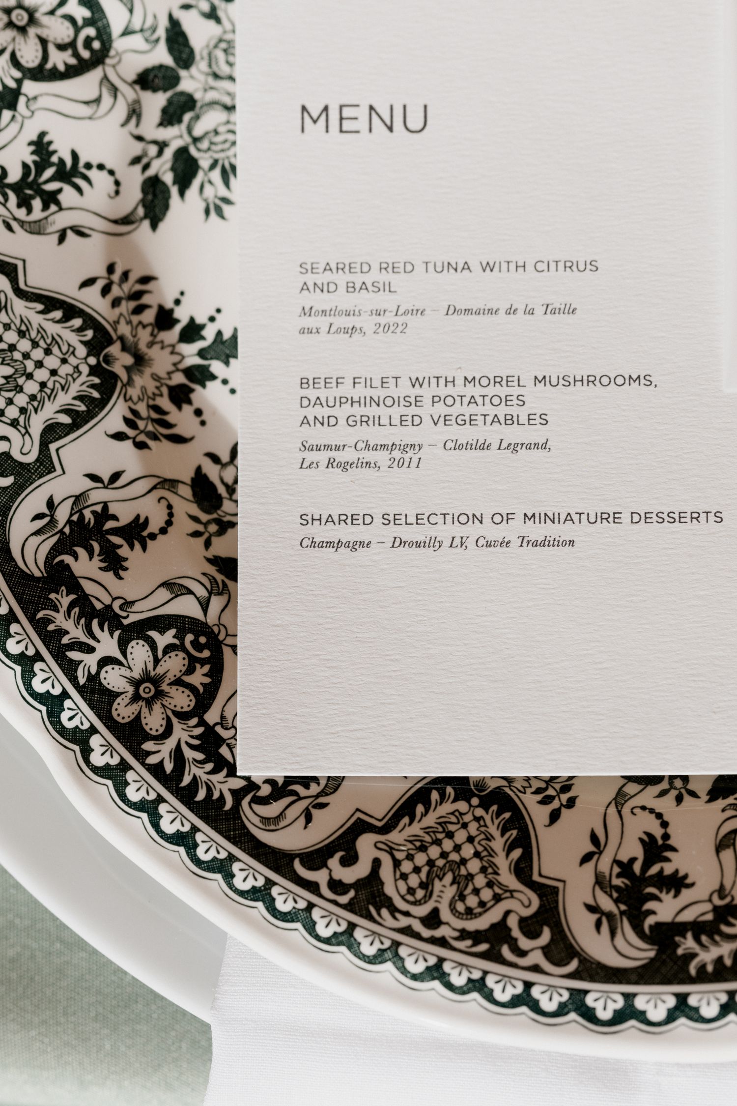Elegant restaurant menu card with ornate black and white decorative border pattern displayed on white plates. Paris wedding photographer