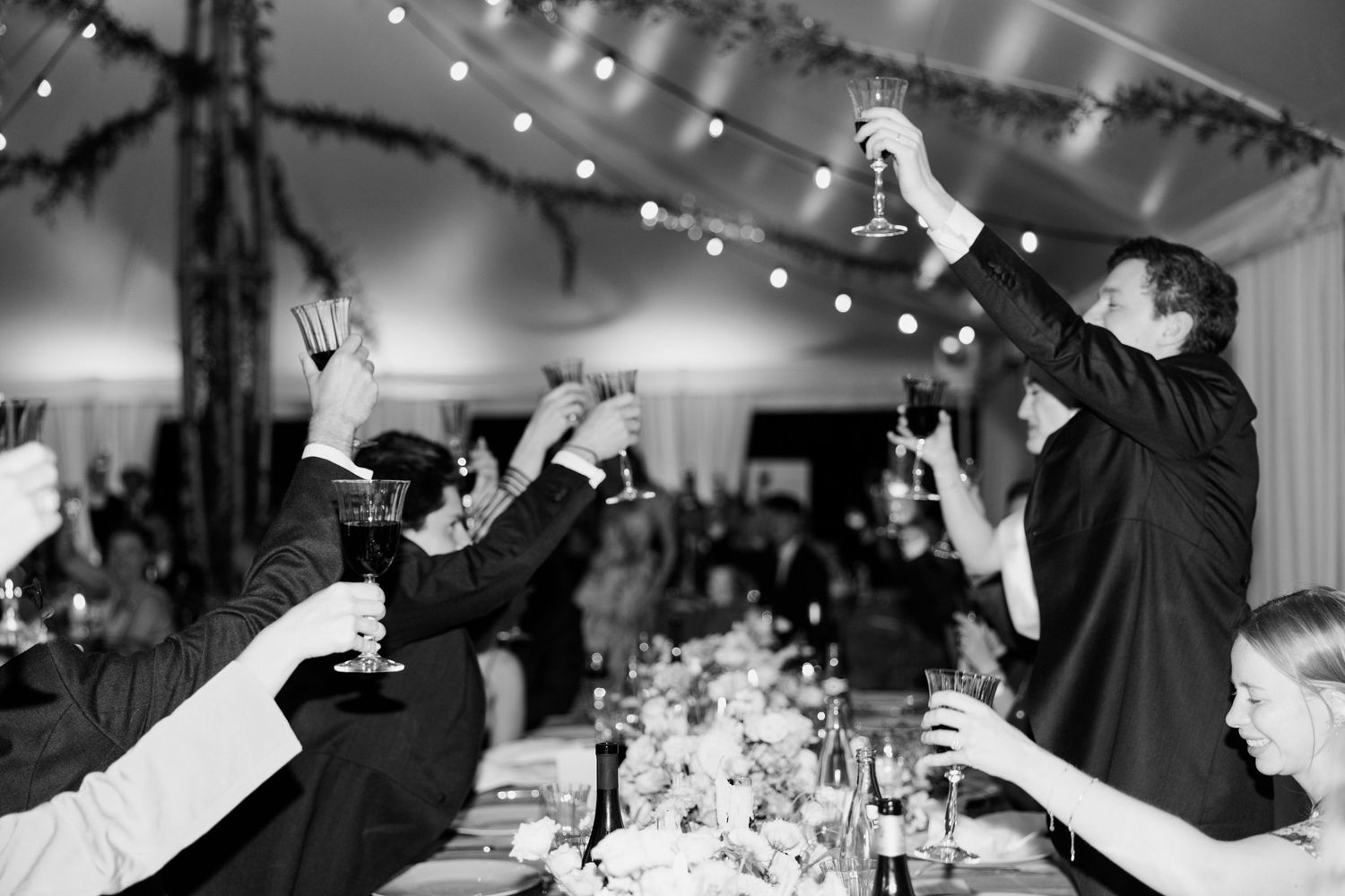 Wedding guests dancing and celebrating on the dance floor during a black and white reception party.