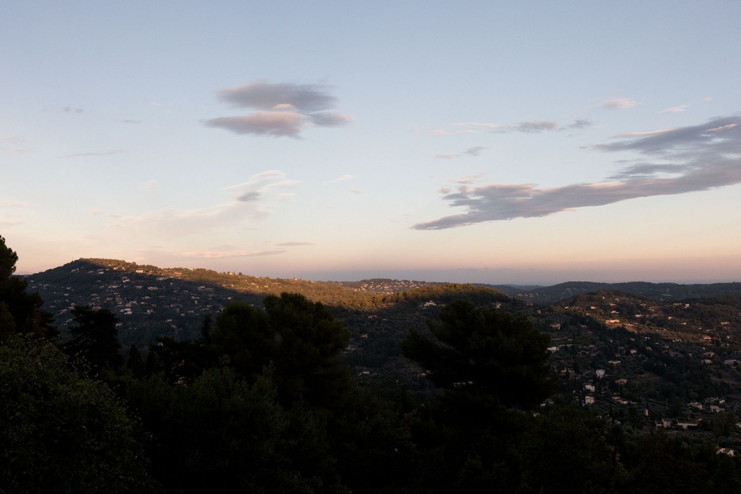 Panoramic sunset view over a hillside town with mountains in the distance and colorful clouds in the sky. Photographe mariage provence